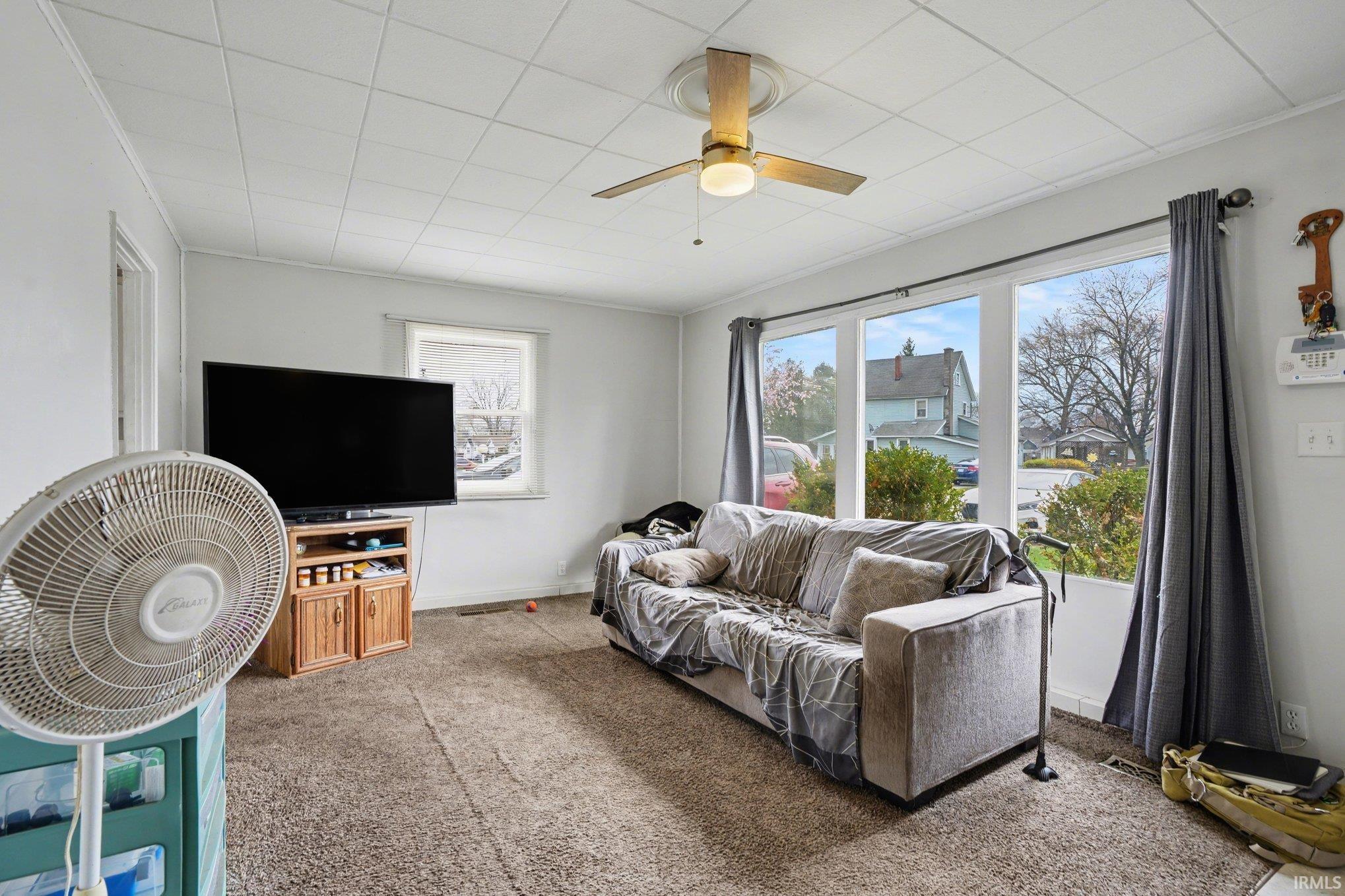 Living area featuring a textured ceiling, a ceiling fan with light fixture, and a large picture window offering exterior views