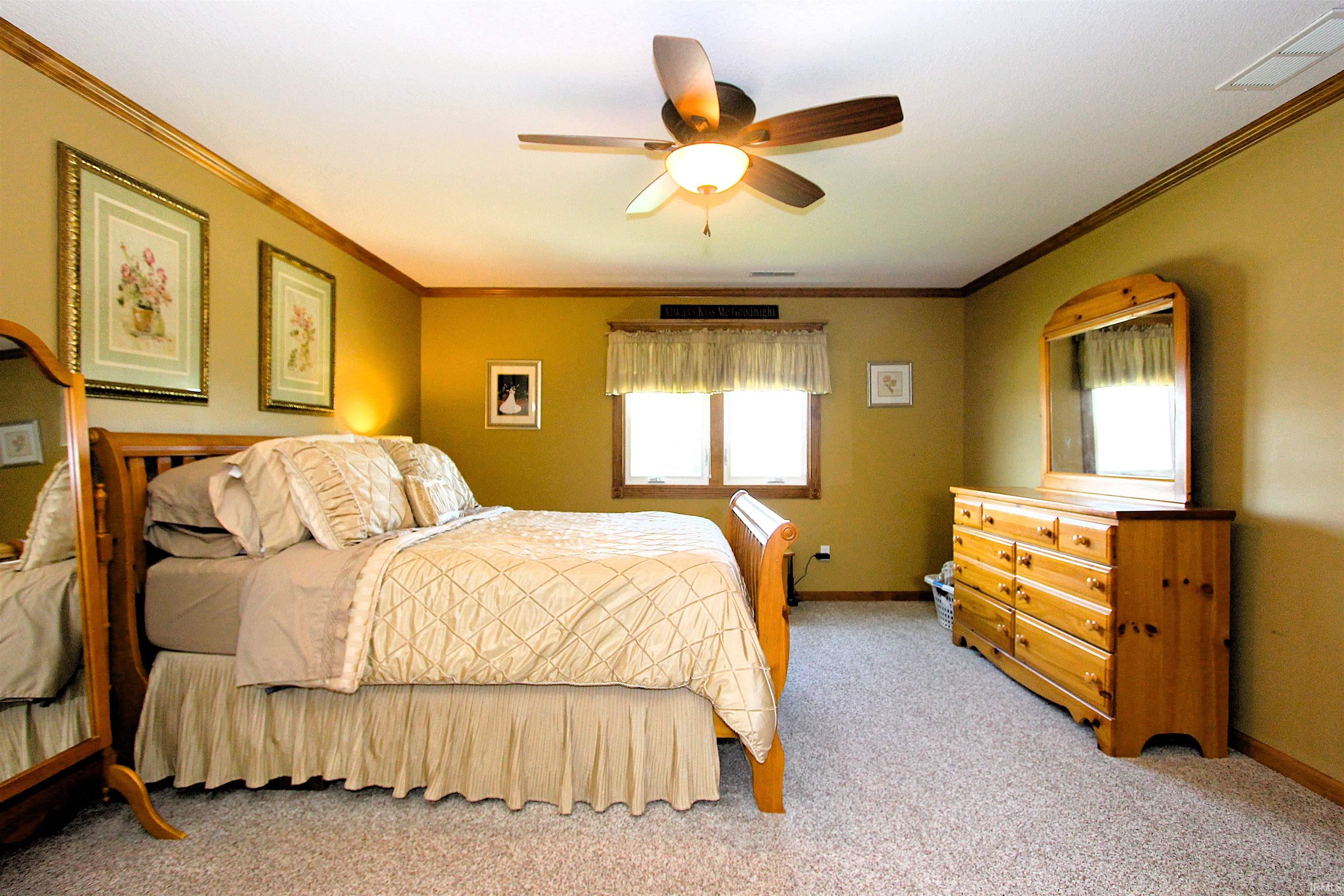 Carpeted room featuring a ceiling fan with integrated lighting, wood-trim windows, and crown molding
