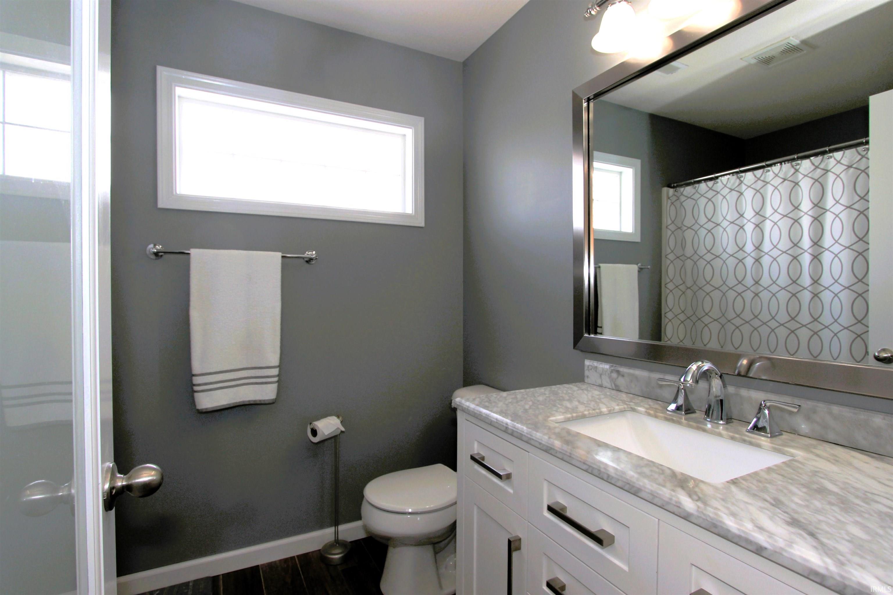 Bathroom featuring a white vanity with brushed nickel hardware, an integrated sink, and a stone countertop
