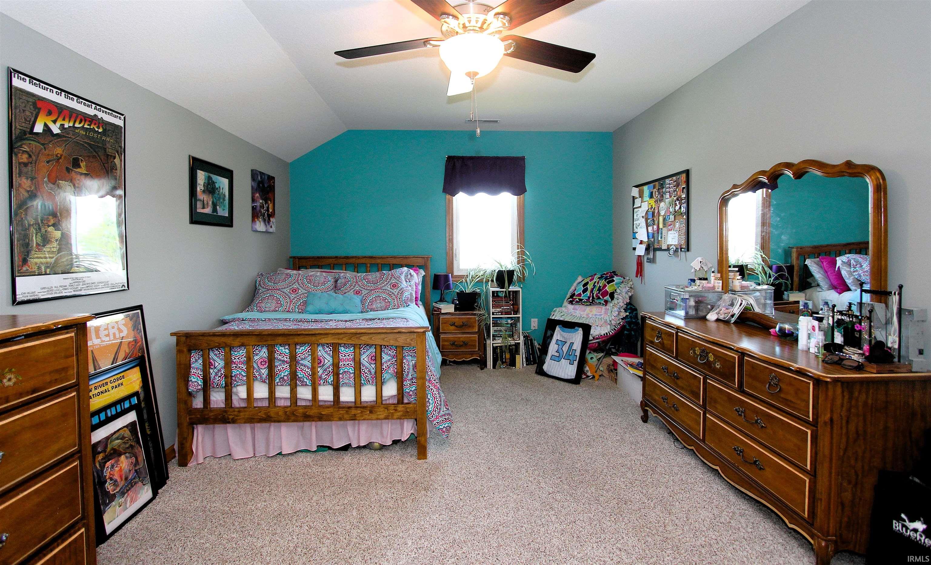 Carpeted room featuring a ceiling fan with light fixture, window with valance, and a distinctive accent wall