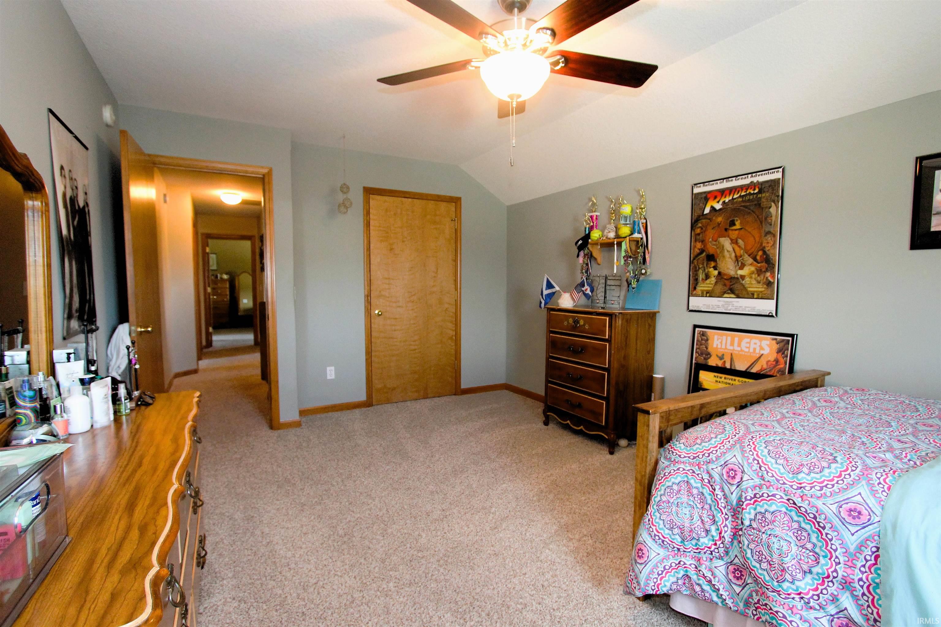 Spacious room featuring vaulted ceilings, light gray wall paint, and plush carpet flooring