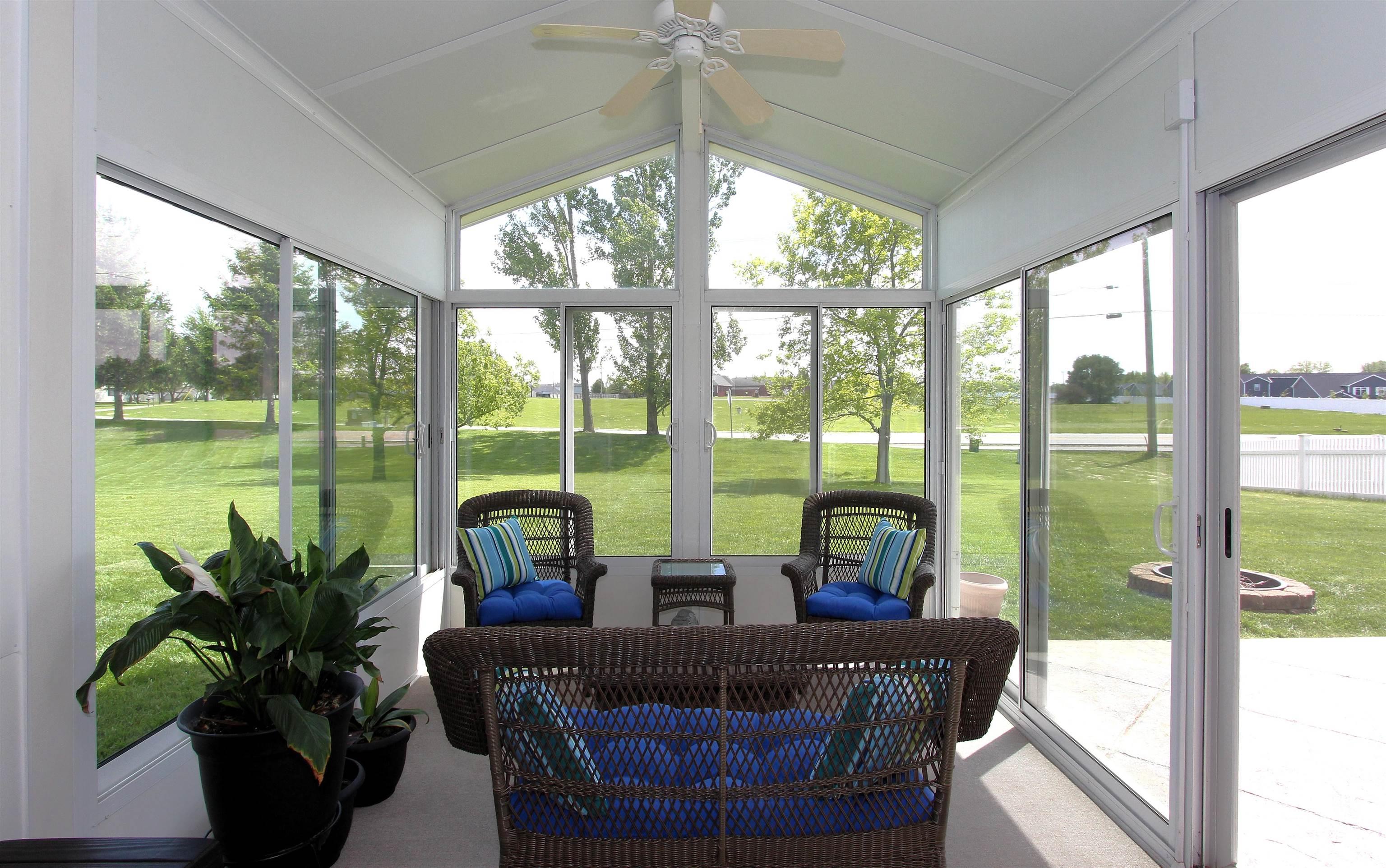Sunroom featuring a vaulted ceiling with a ceiling fan, multiple large windows, and a sliding glass door