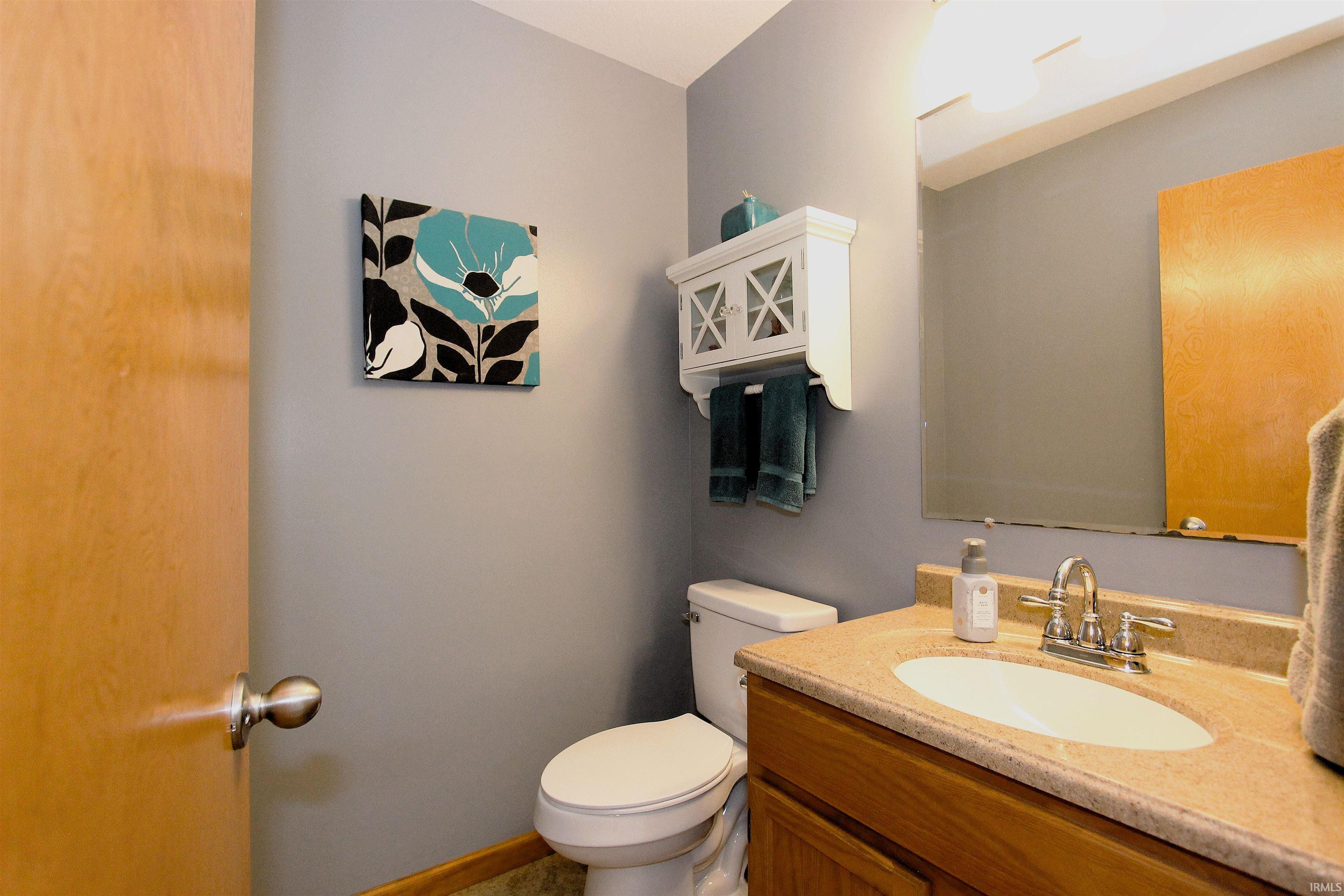Bathroom featuring wood-finish vanity with an oval sink, polished chrome faucet, and a mirror above