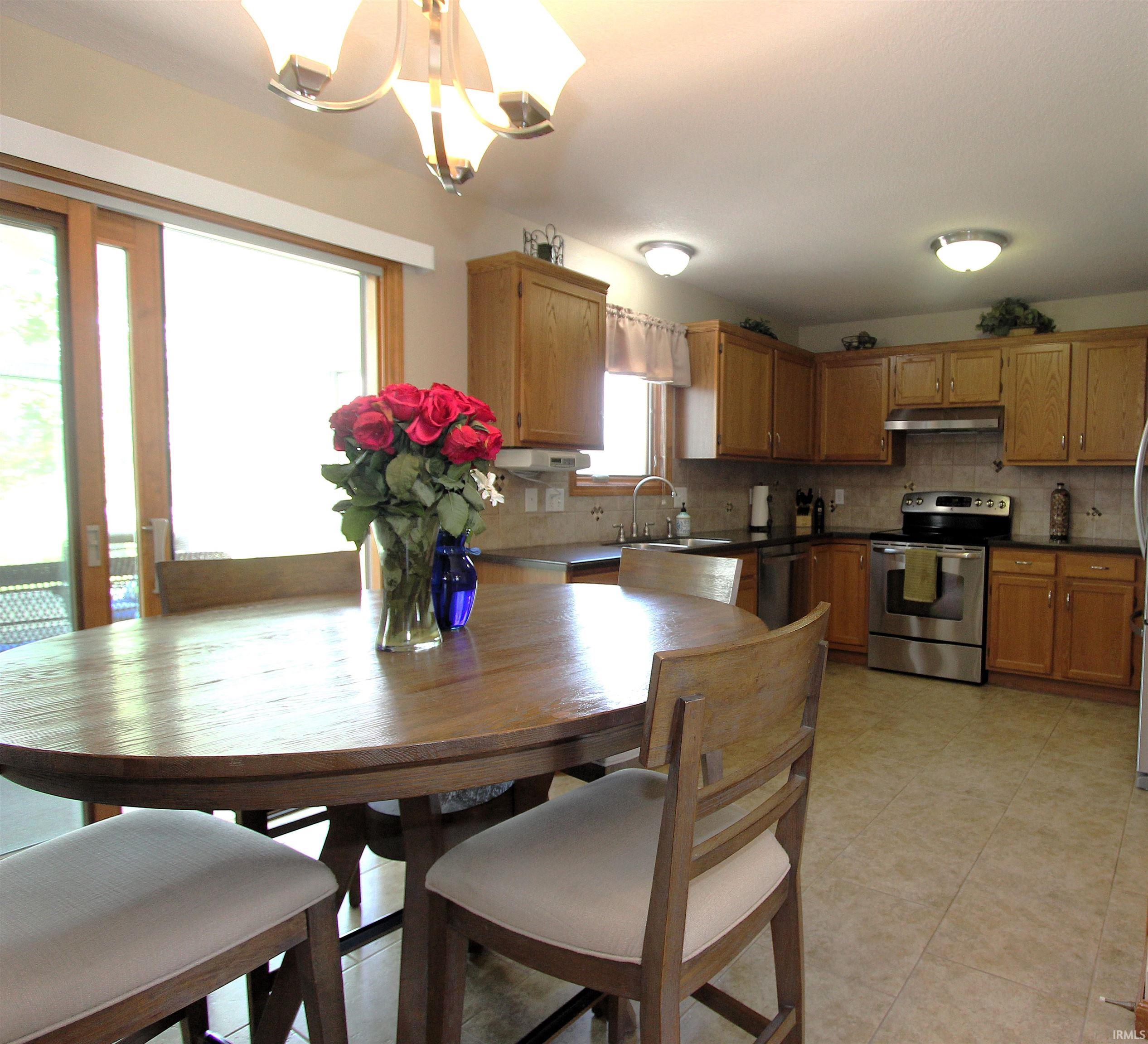 Eat-in kitchen featuring wood cabinetry, stainless steel appliances, dark countertops, and tile flooring