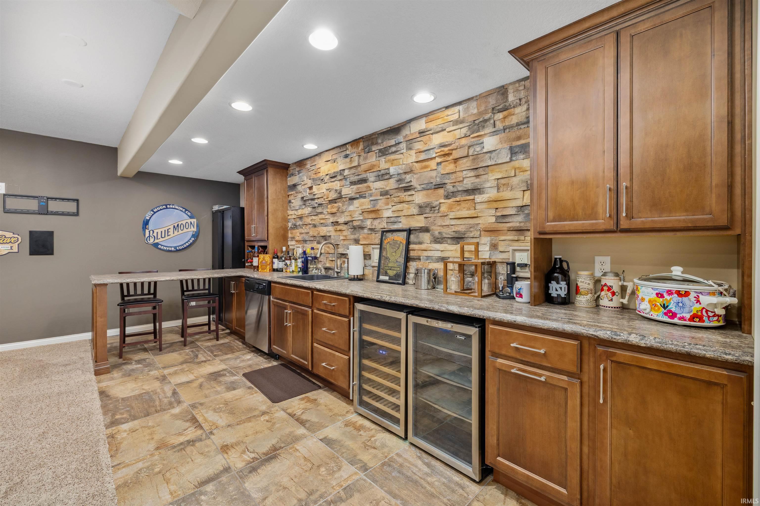 Entertainment space featuring a stone accent wall, recessed lighting, and a built-in bar with wood-finish cabinetry