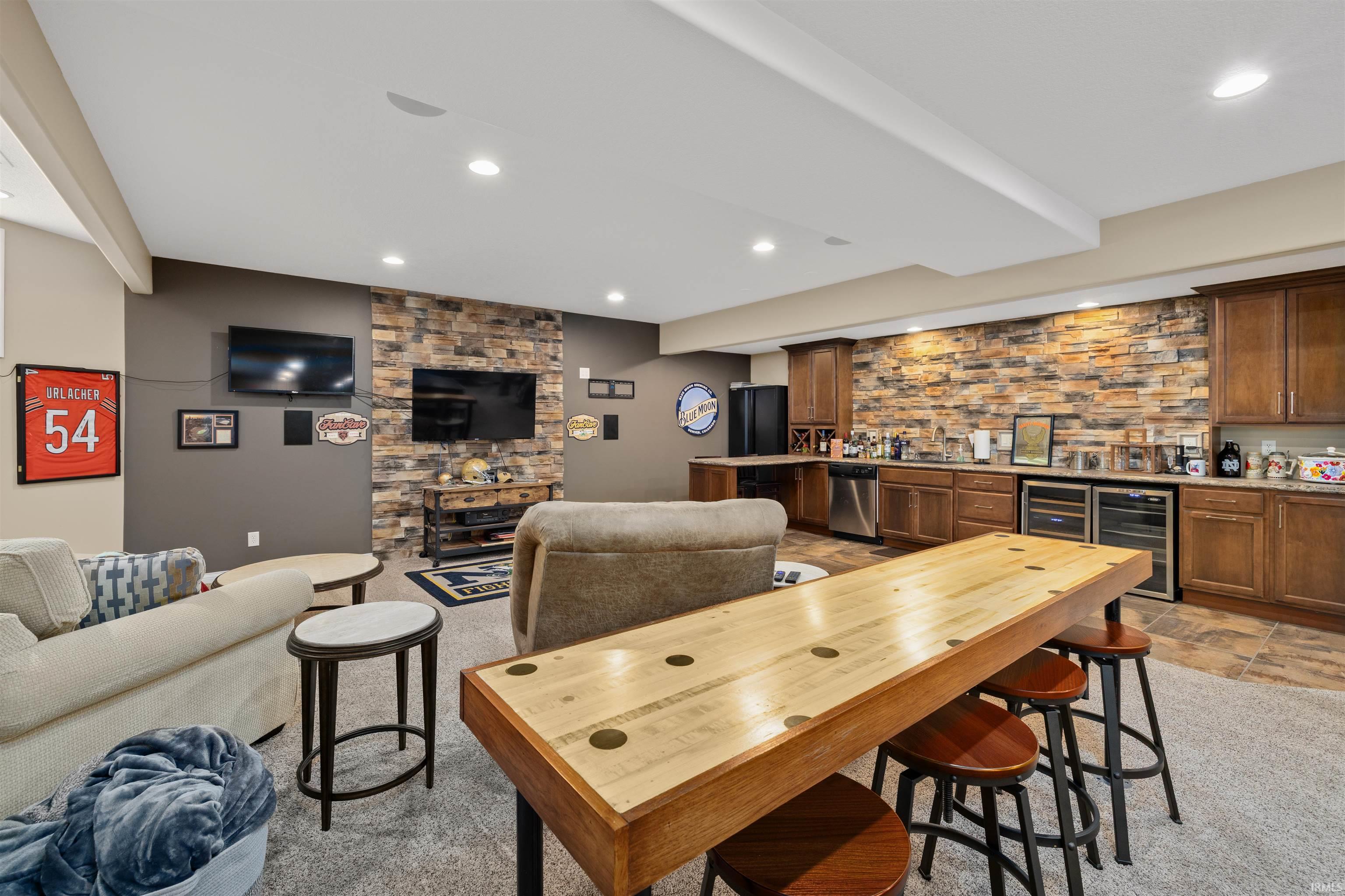 Spacious entertainment area featuring a stone accent wall, recessed lighting, and a built-in wet bar with wood-finish cabinetry