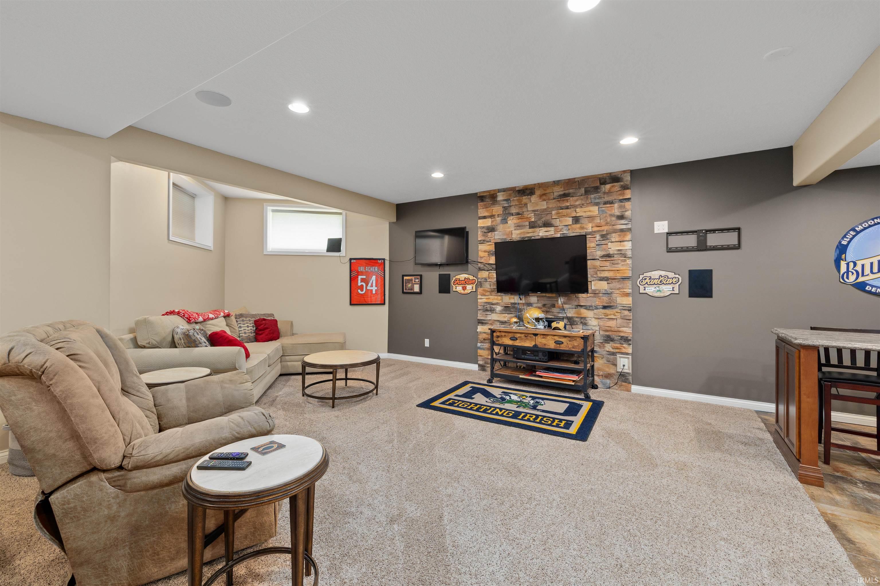 Spacious recreation room featuring recessed lighting, a stone accent wall, and light-toned carpeting