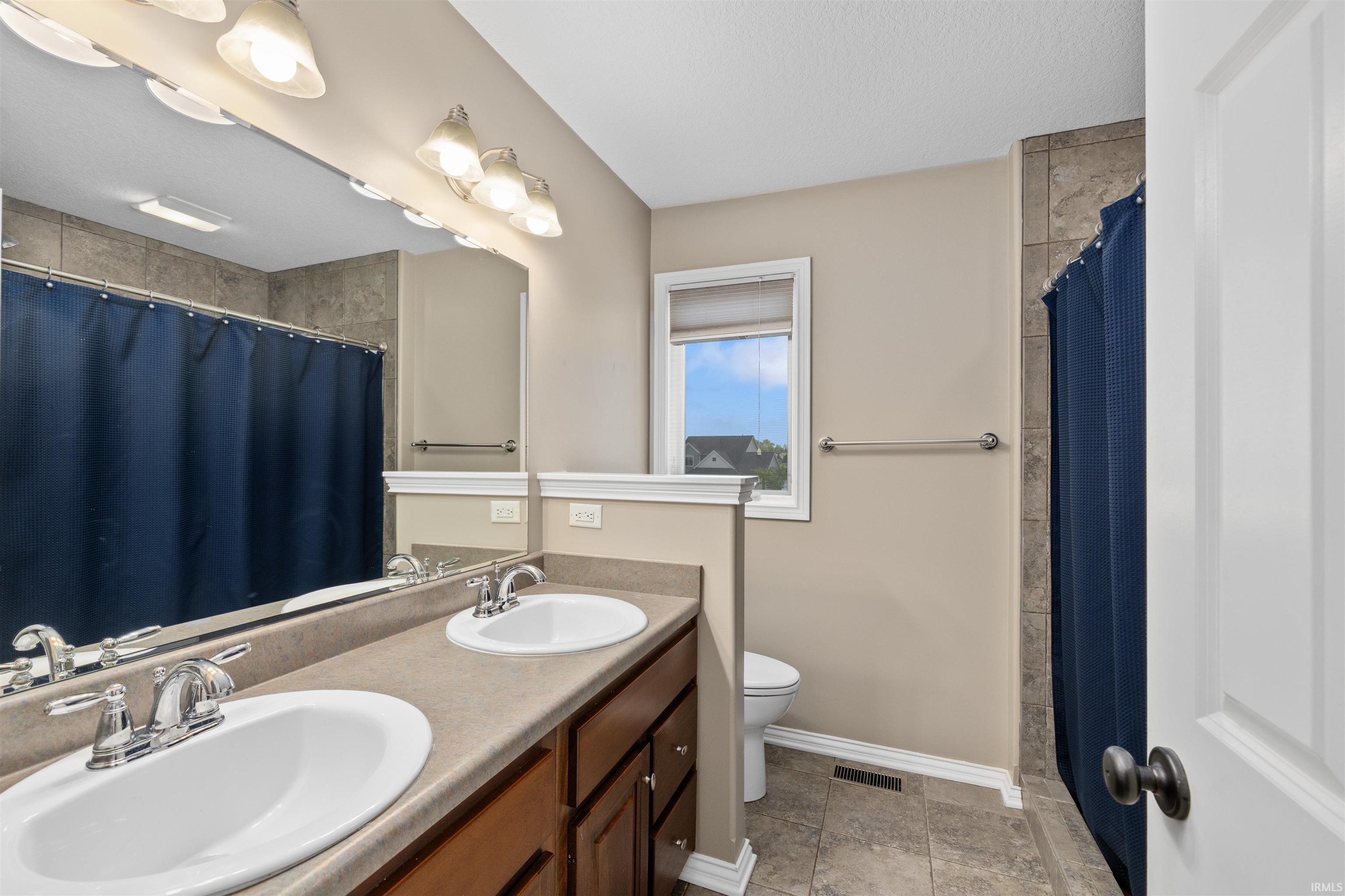 Bathroom featuring a dual vanity with undermount sinks, wood-finish cabinetry, and a neutral-toned countertop