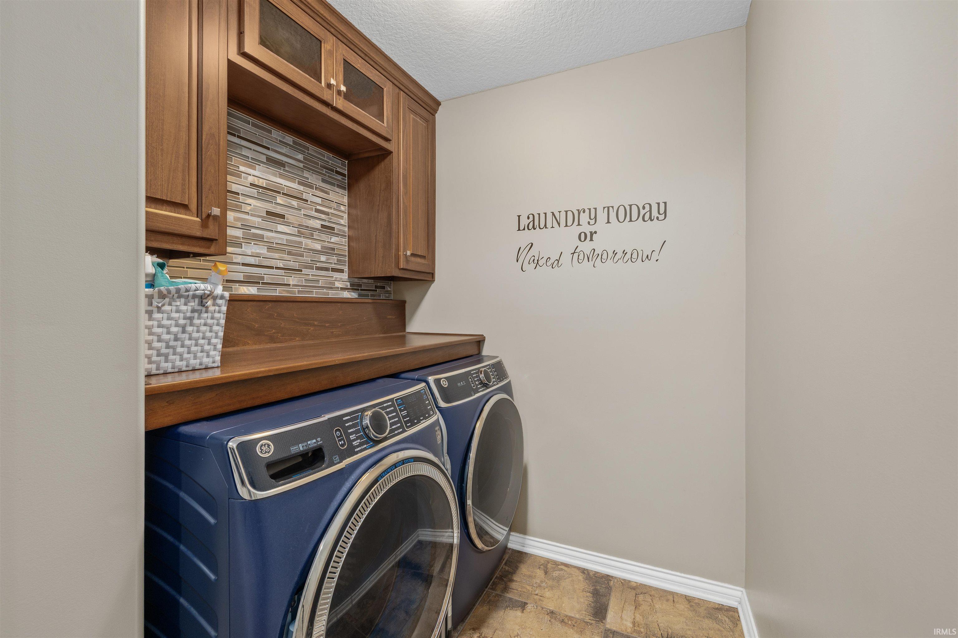 Dedicated laundry area featuring wood-finish cabinetry, a tiled backsplash, and wood-finish countertop