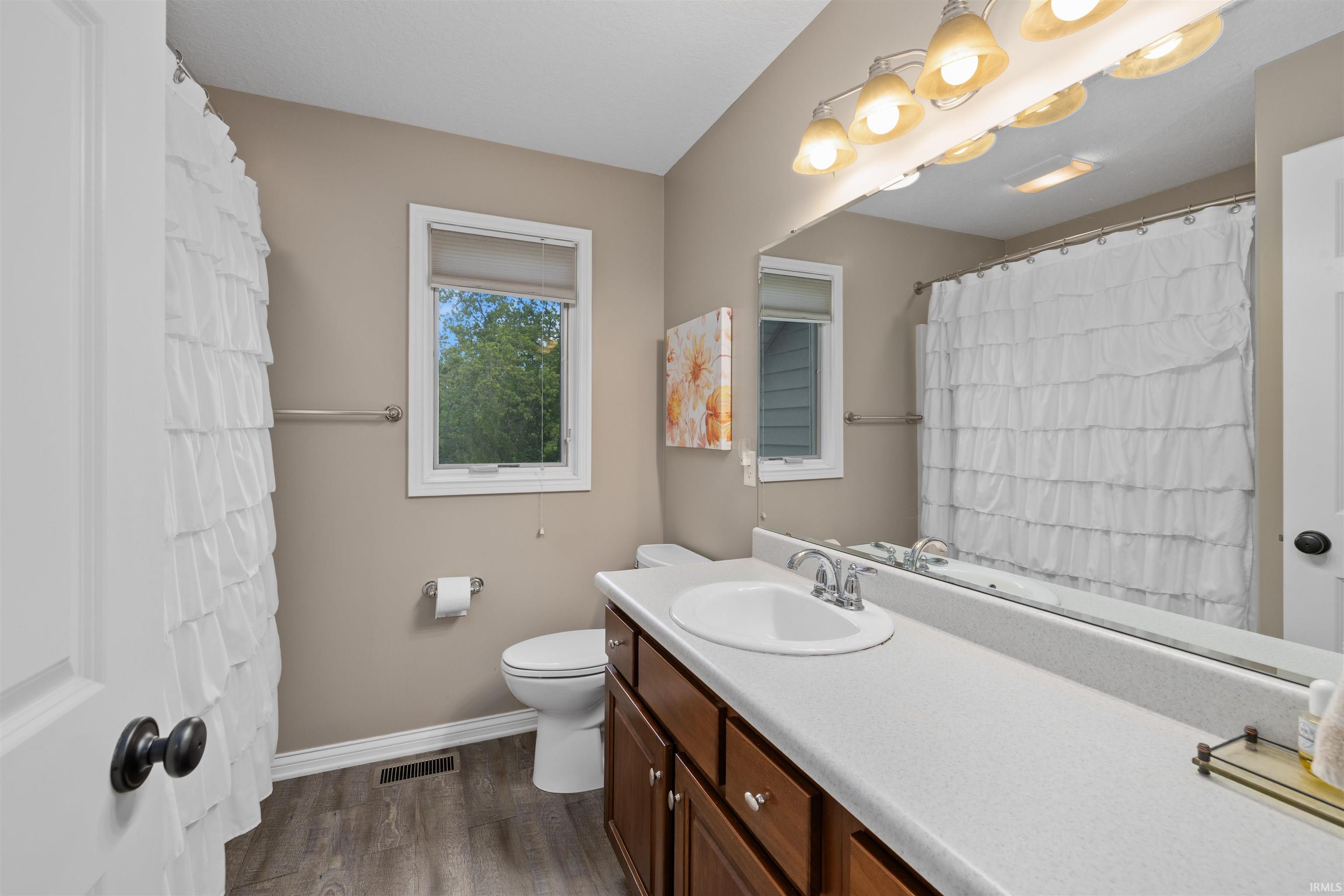 Bathroom featuring a wood-finish floor and a window with blinds