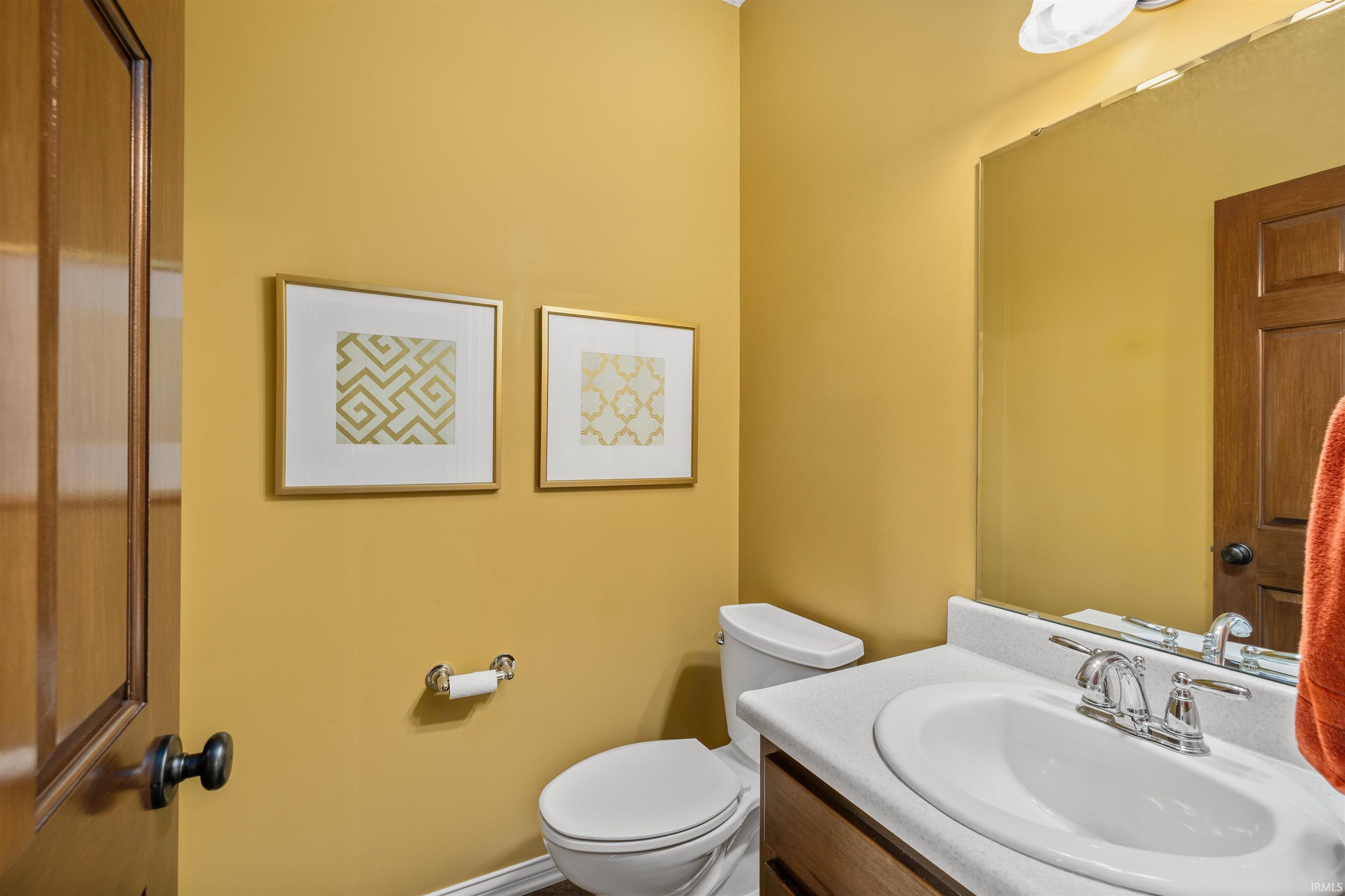 Powder room featuring a wood-panel door, white vanity with an undermount sink, chrome faucet, and a wall-mounted mirror