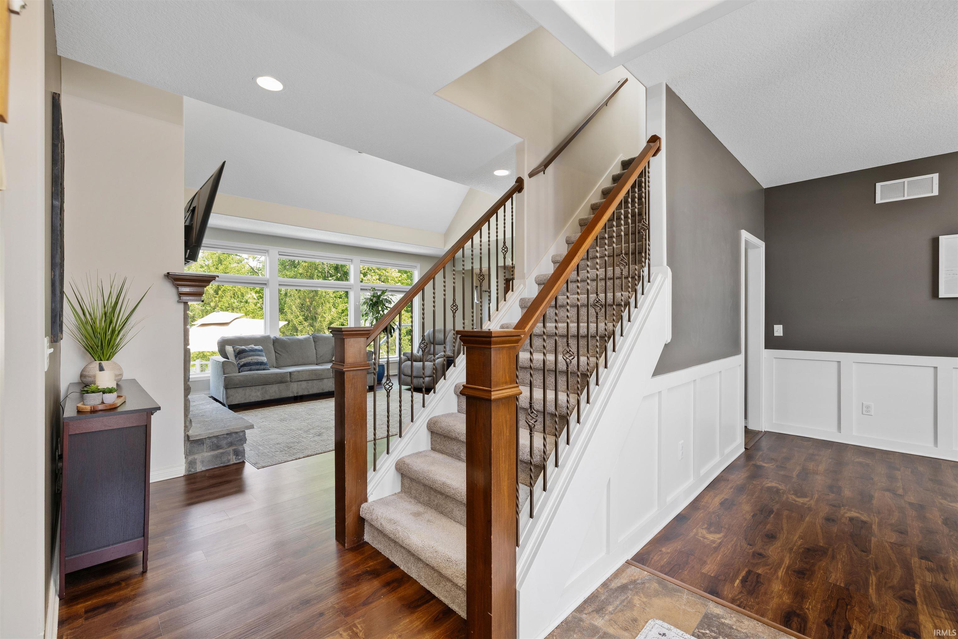 Grand staircase featuring wood newel posts, wrought iron spindles, and carpeted treads