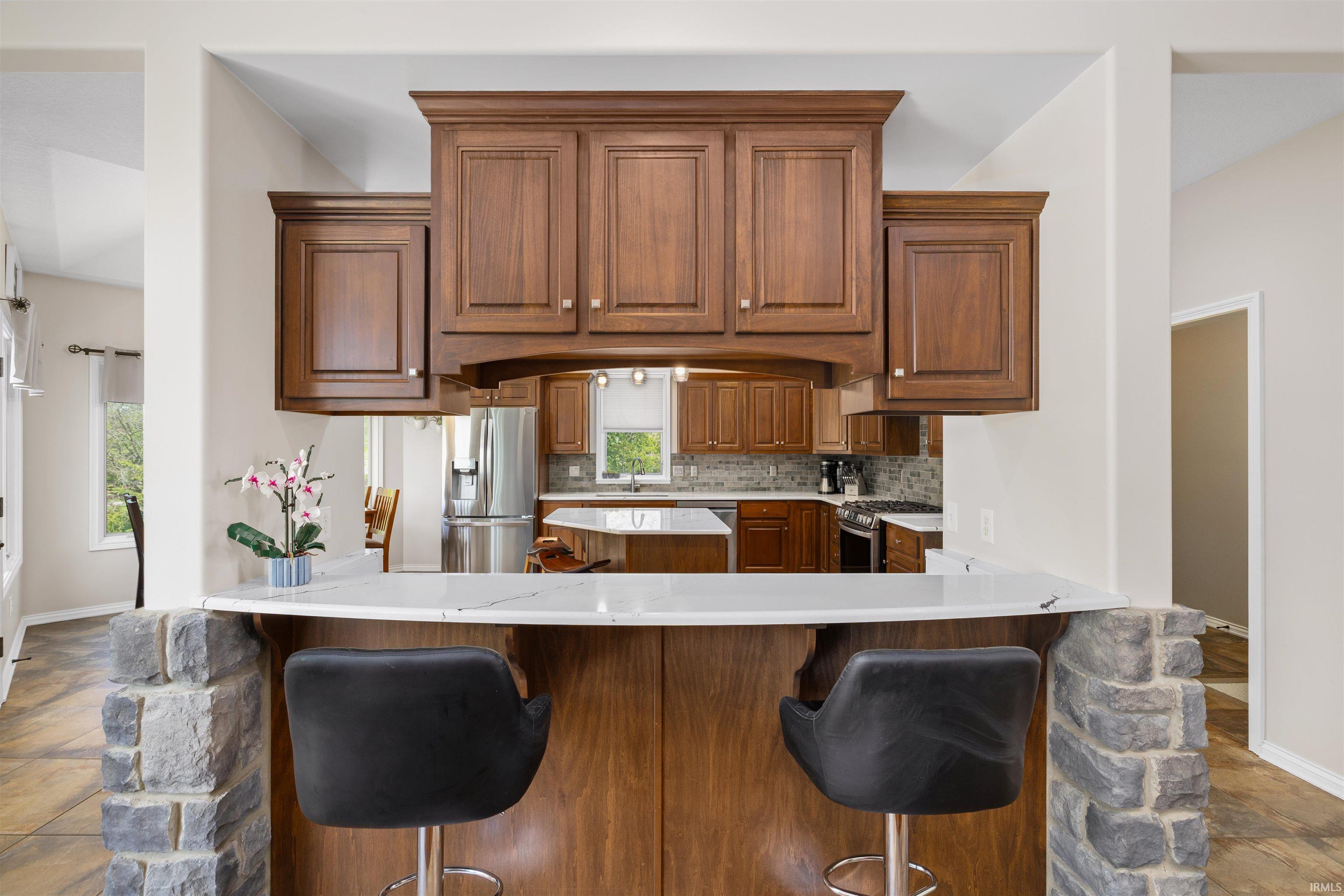 Kitchen pass-through featuring a stone-clad half-wall, wood-finish cabinetry, and a light-toned countertop