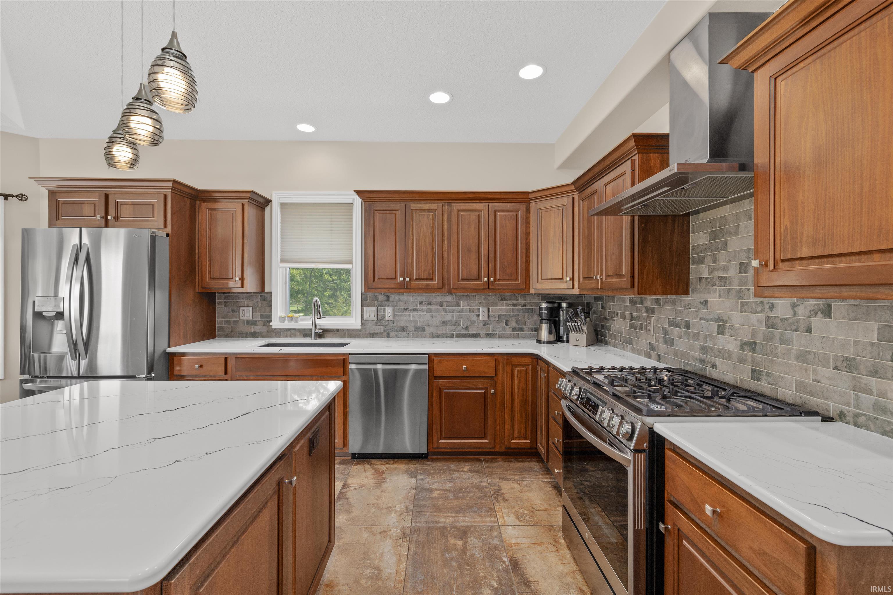 Kitchen featuring wood cabinetry, white countertops, tile flooring, stainless steel appliances, and pendant lighting