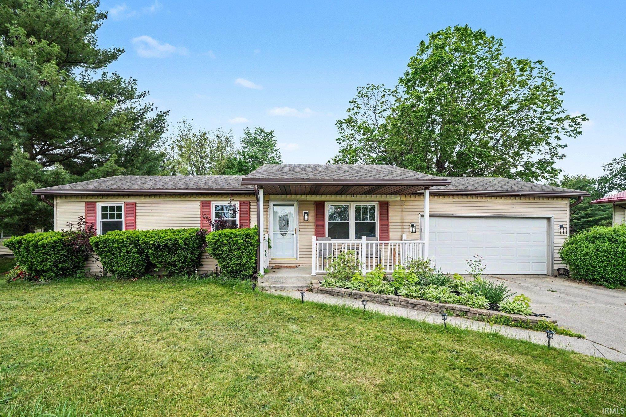 Ranch-style residence featuring beige siding, red window shutters, and a covered front porch with white railings