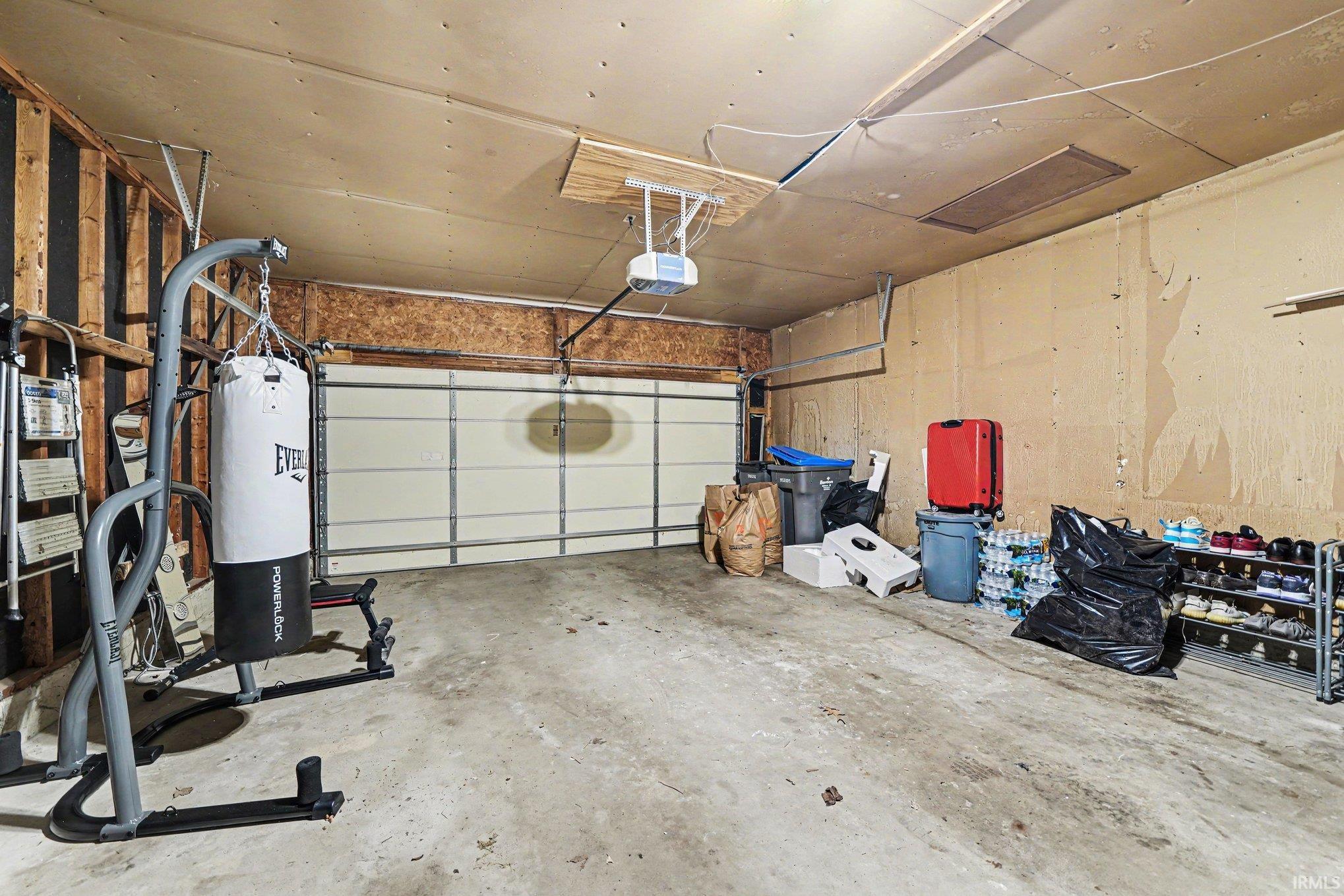 Attached garage featuring a concrete floor, exposed wood framing, and an overhead garage door