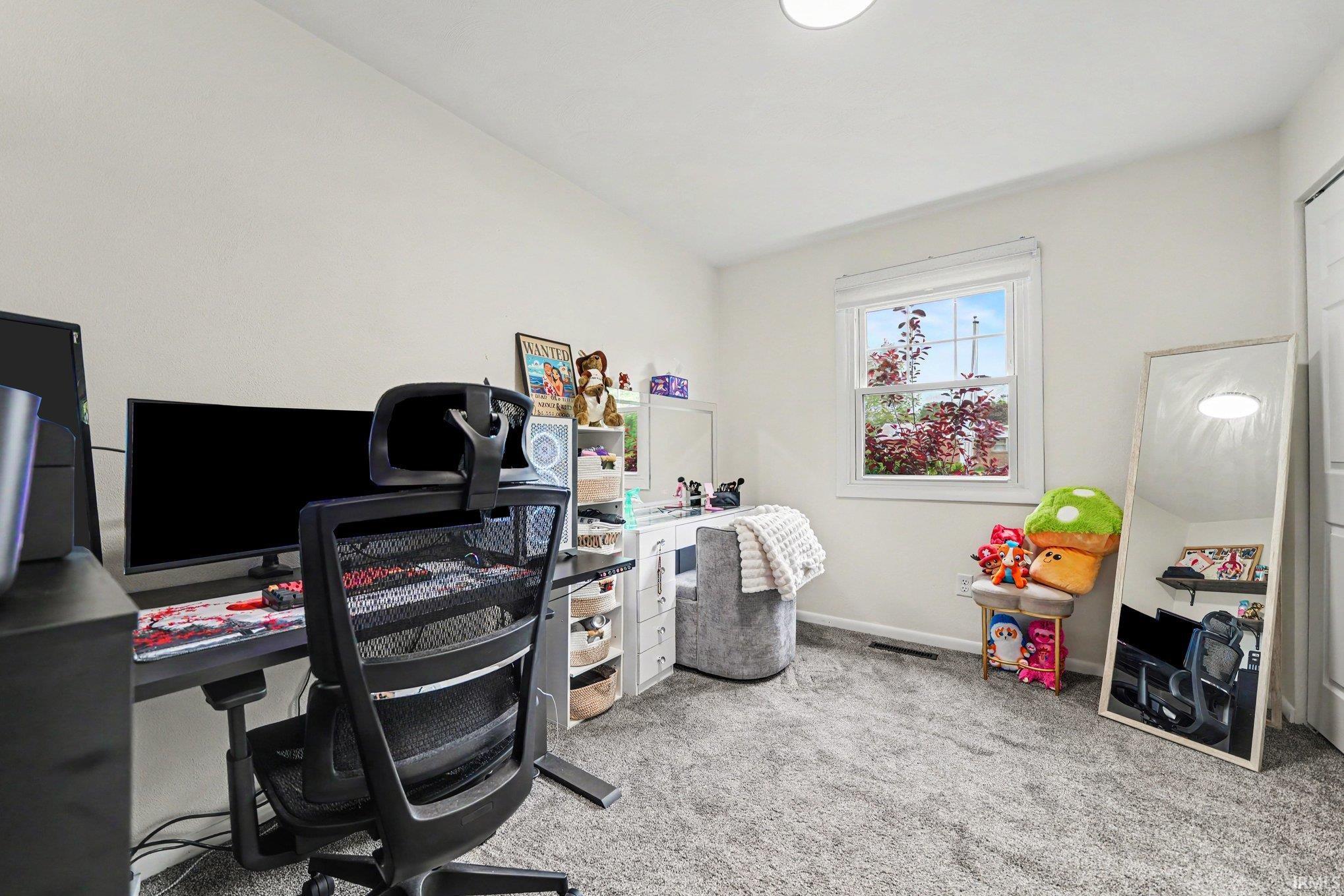 Bright room featuring a single window with outdoor foliage, light gray carpet, and white walls