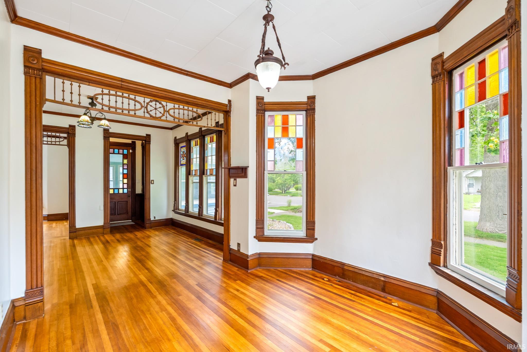 Hardwood flooring throughout featuring decorative wooden trim and a detailed archway
