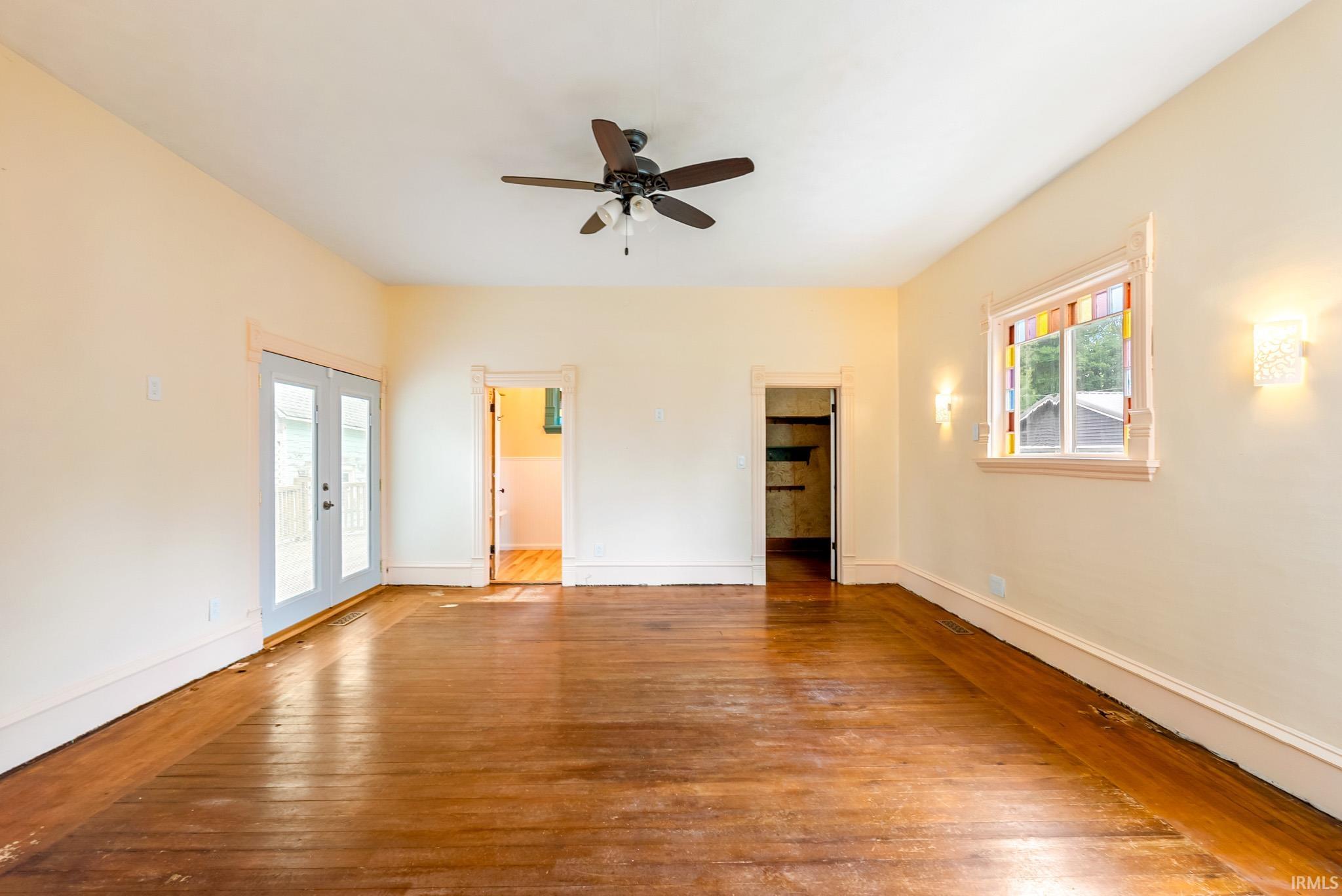 Spacious room featuring wood-finish flooring, light-toned walls, and a ceiling fan