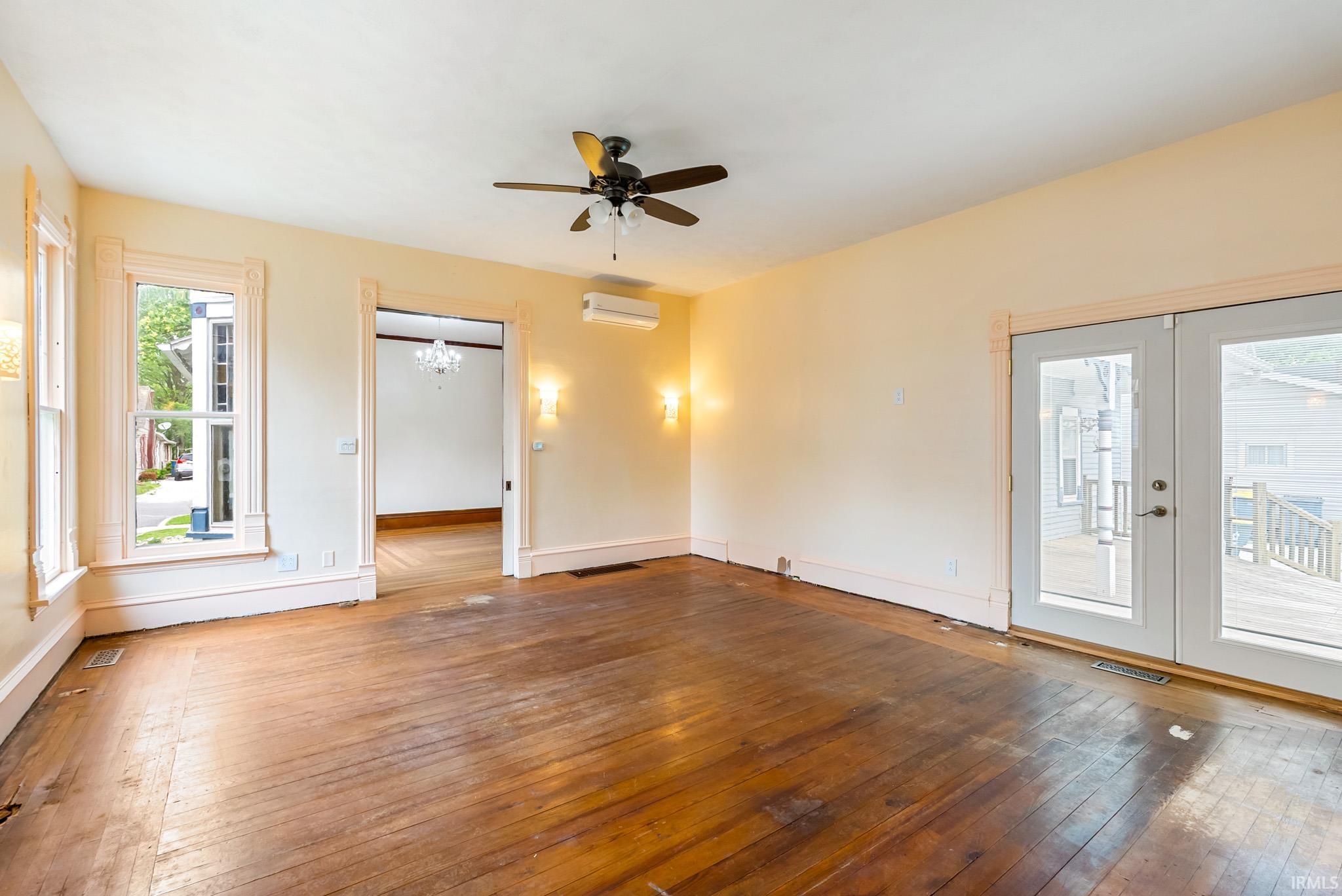 Room featuring wood-finish flooring, a ceiling fan, and sconce lighting