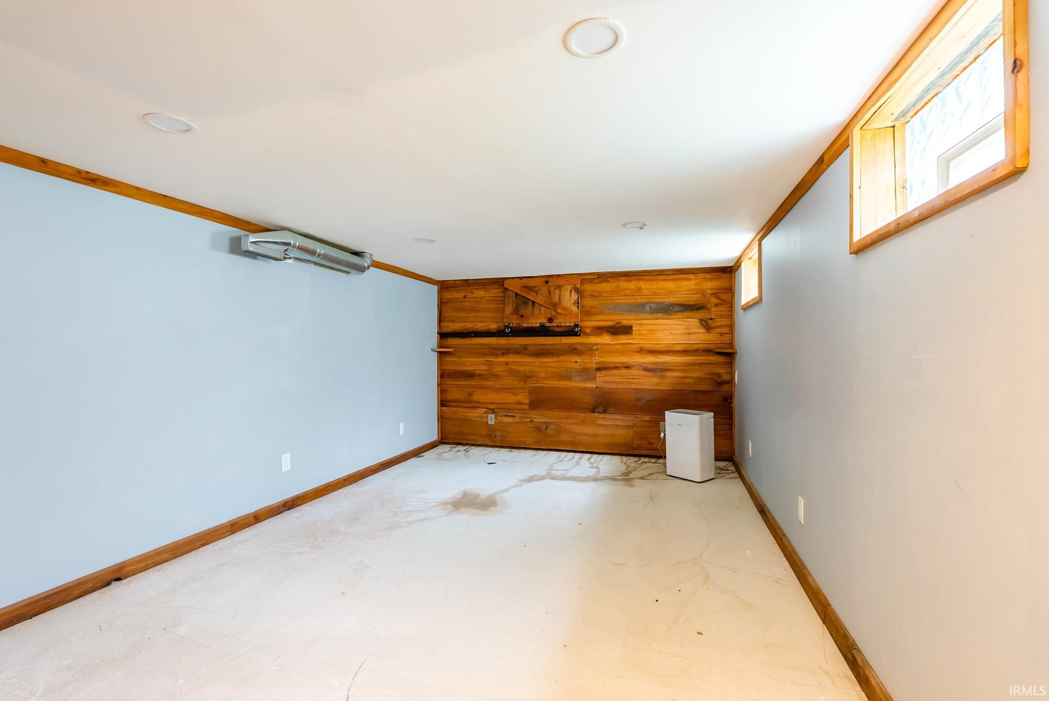 Finished room featuring light blue walls, wood-finish trim, recessed lighting, and a wood-paneled accent wall