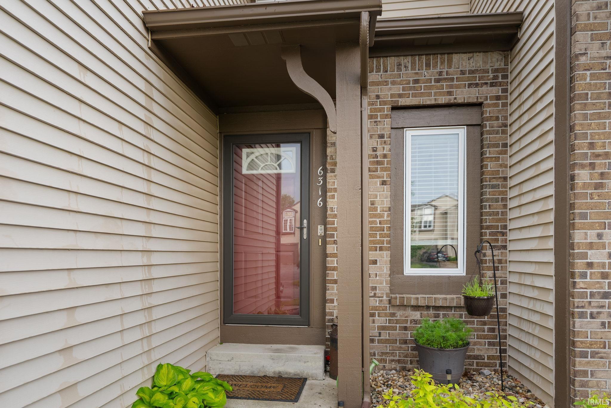 Entryway featuring a storm door with decorative glass, concrete stoop, and address numbers