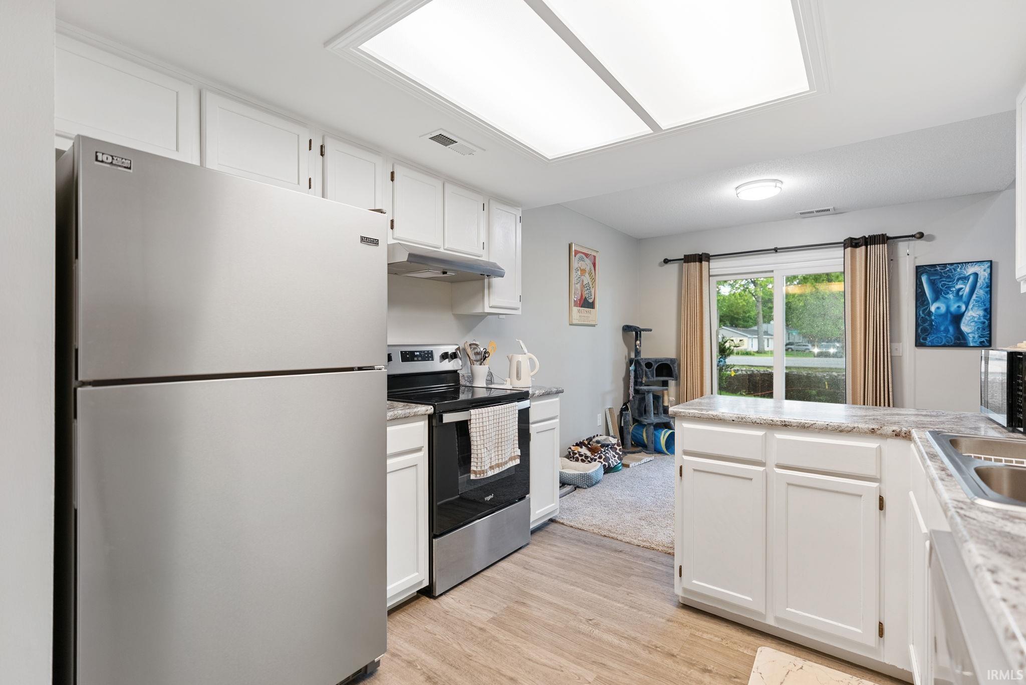 Kitchen featuring stainless steel appliances, white cabinetry, wood-finish flooring, a white countertop, and recessed lighting