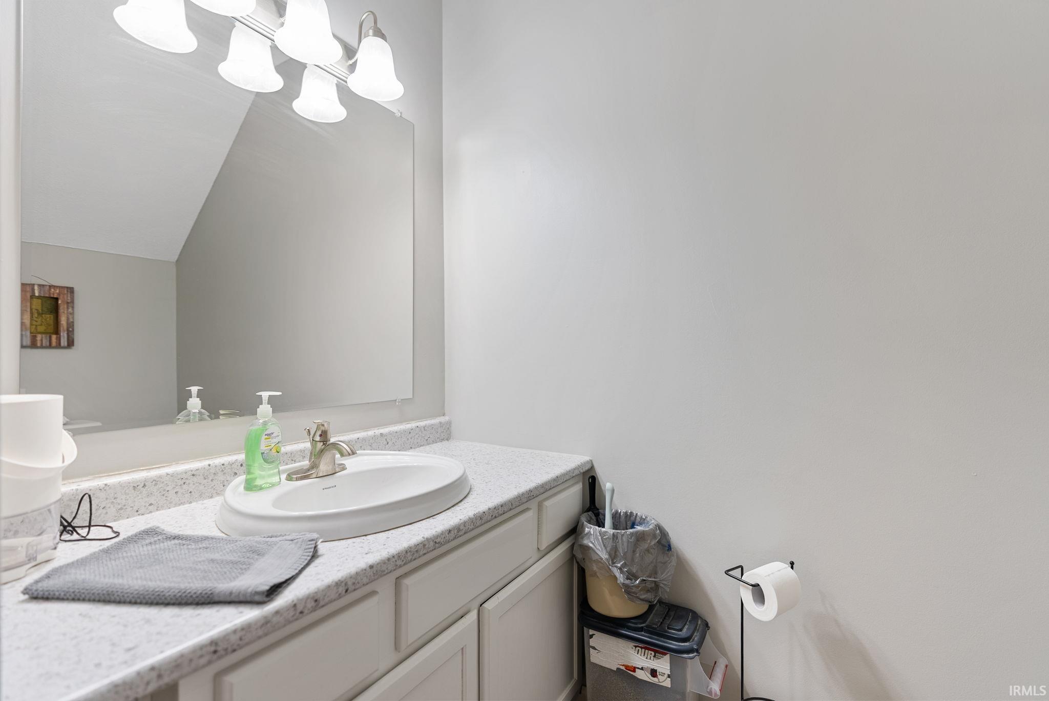 Bathroom vanity featuring a speckled countertop, integrated oval sink, and white cabinetry