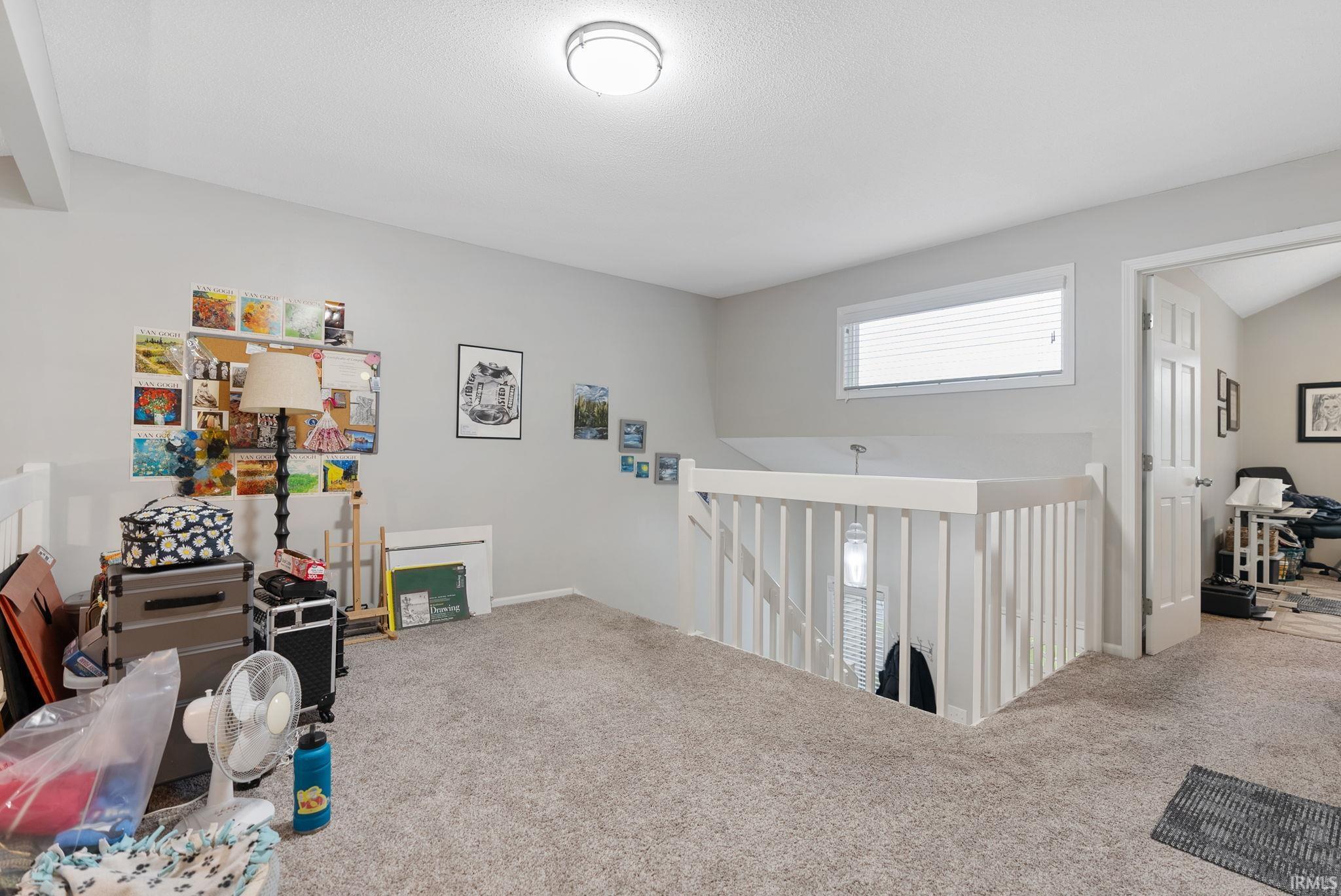 Carpeted landing featuring a white railing and a window with blinds