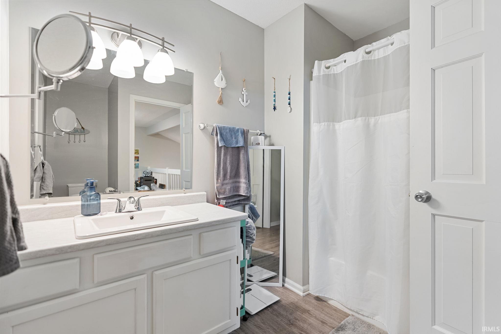 Bathroom vanity featuring a white countertop with an integrated sink, polished chrome faucet, and white paneled cabinetry