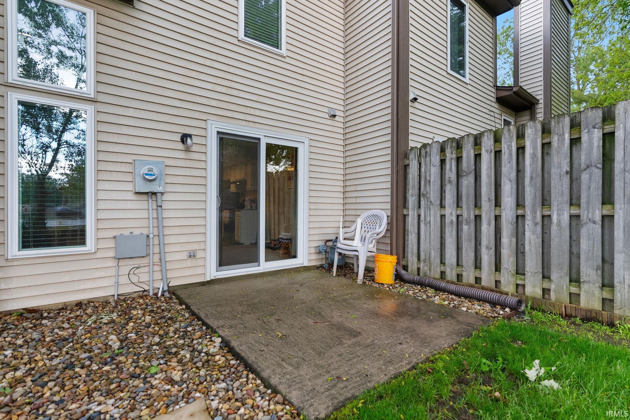 Rear exterior featuring a concrete patio, sliding glass door, and multiple windows