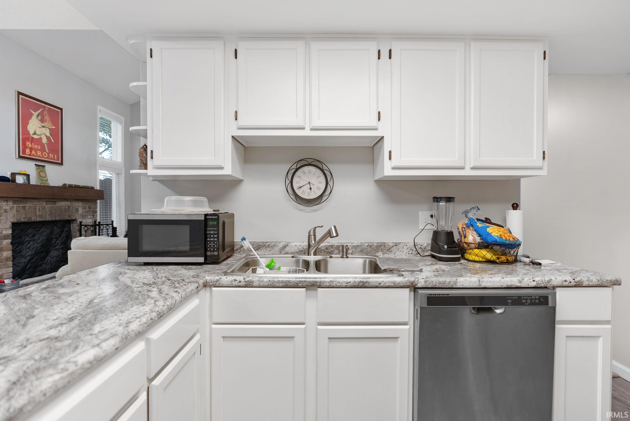 Kitchen featuring white cabinetry, a double basin stainless steel sink, a stainless steel dishwasher, and a light-toned patterned countertop