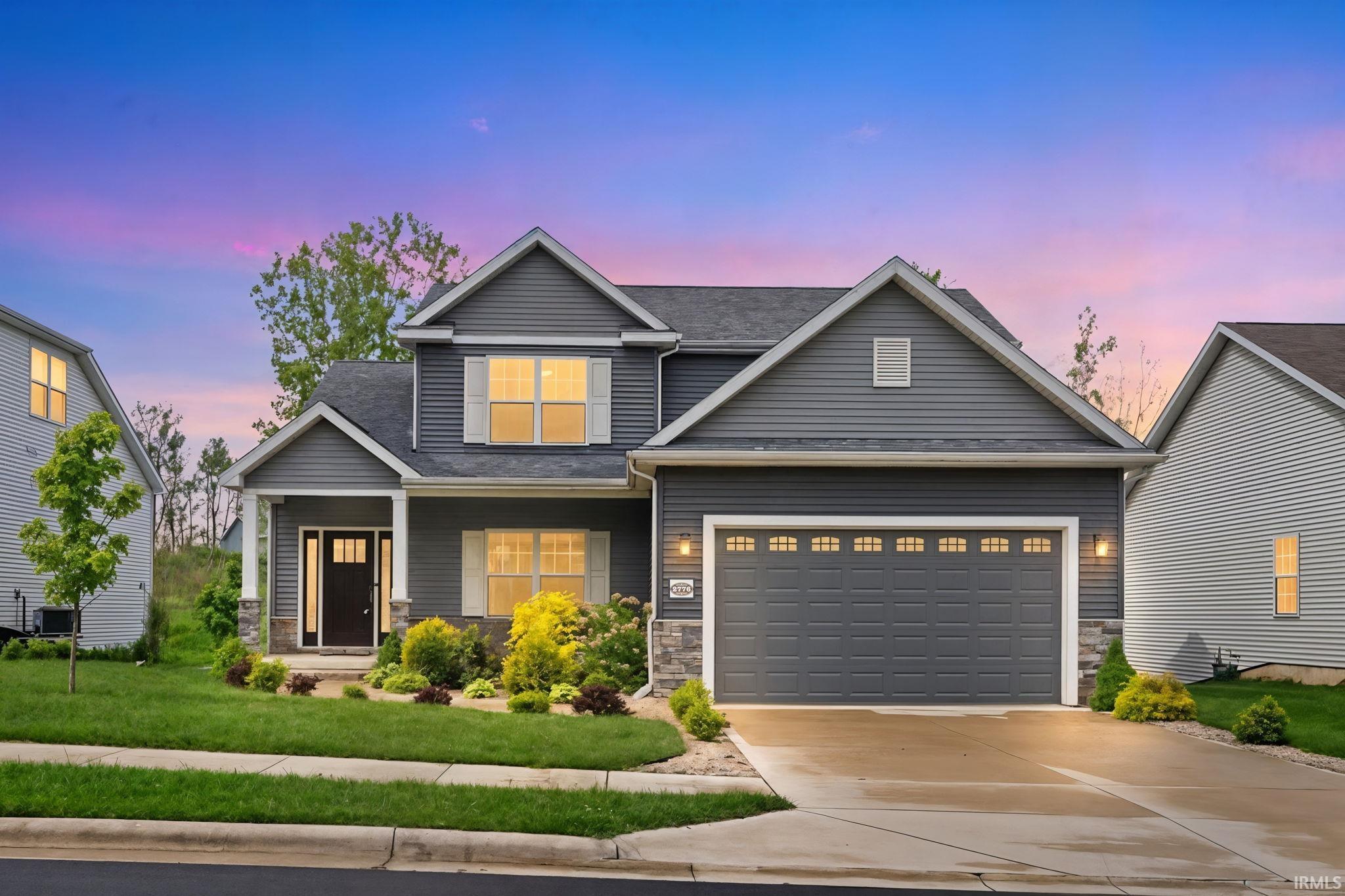 Contemporary two-story residence featuring grey siding, white window shutters, and a dark asphalt shingle roof