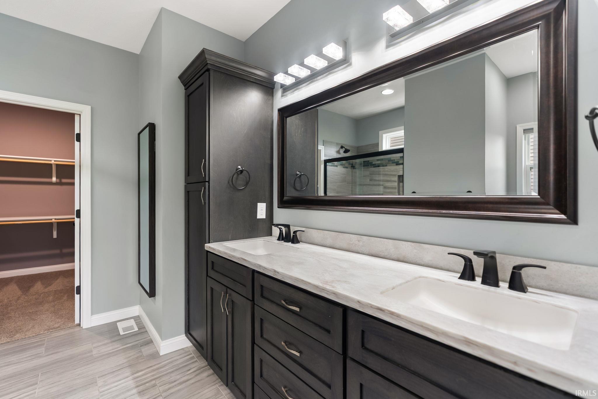 Dual vanity with dark wood-finish cabinetry and light countertops
