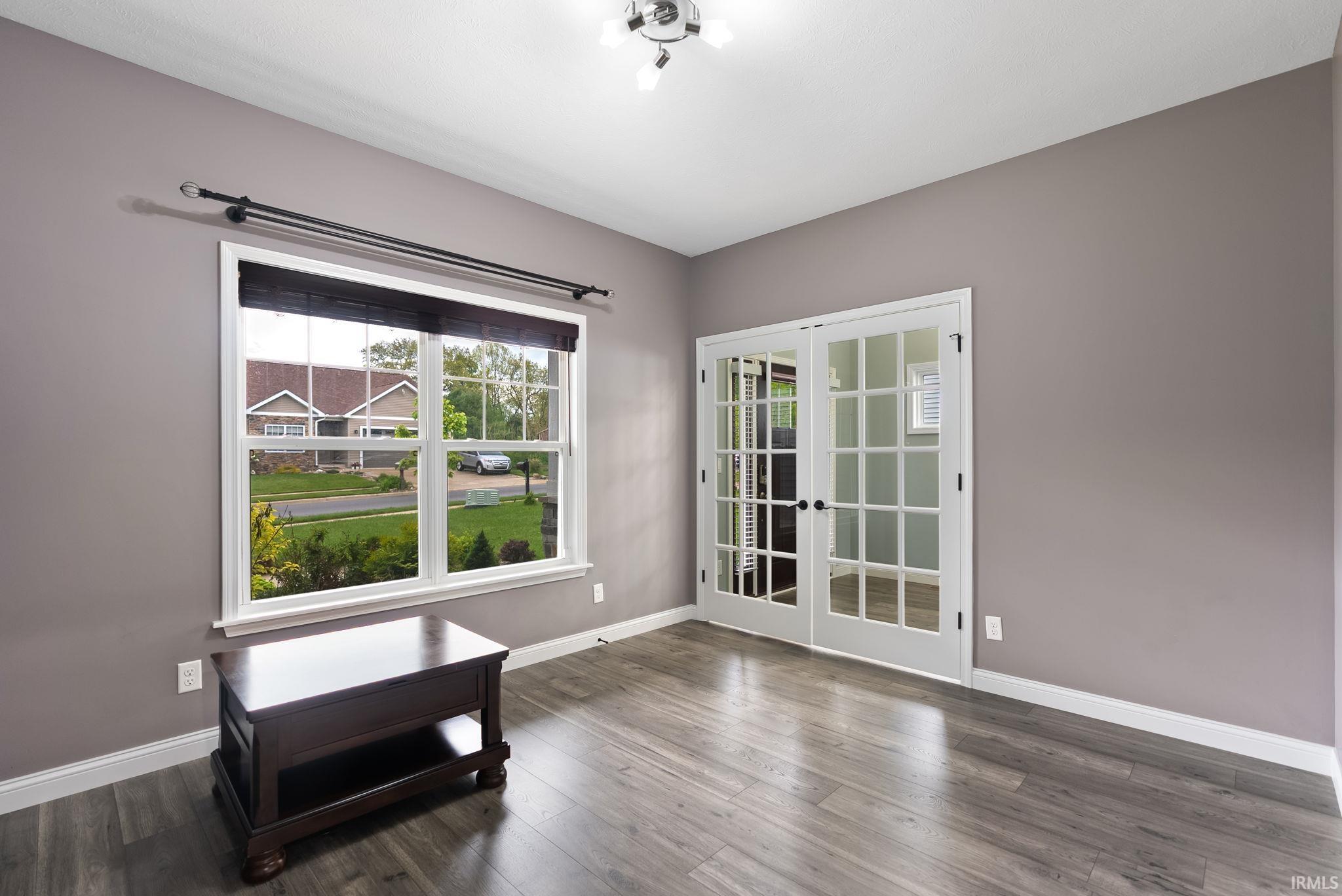 Room featuring light gray walls, wood-finish flooring, white baseboards, and a window with white trim