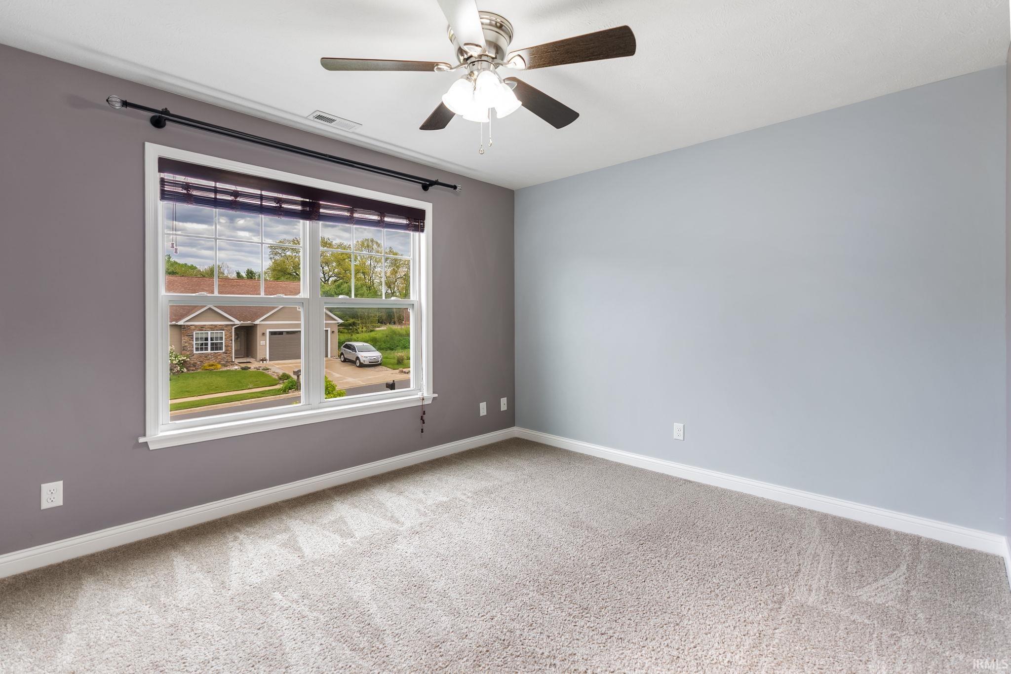 Room featuring a window with white trim, a ceiling fan with light fixture, light gray carpeting, and two-tone wall paint