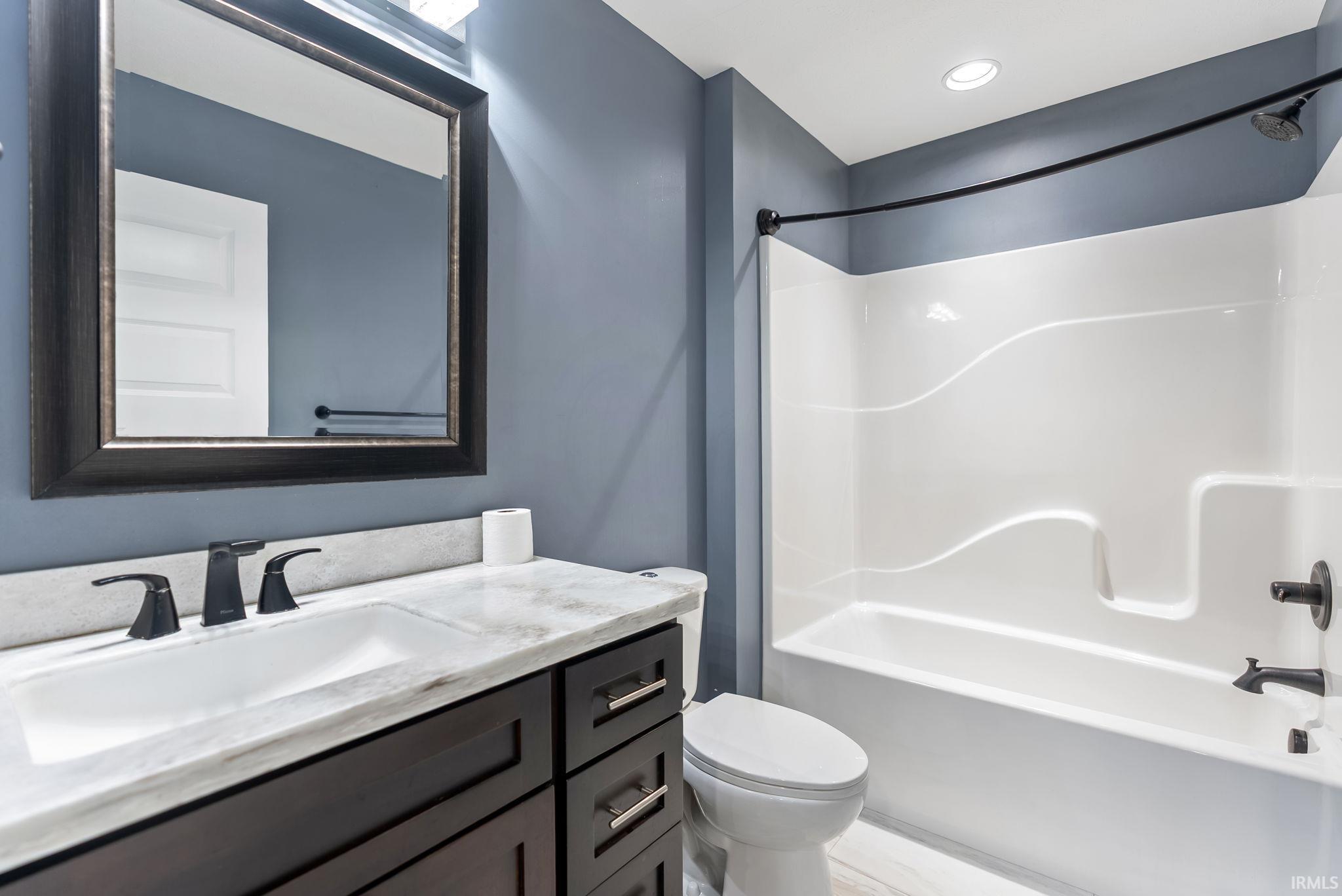 Bathroom featuring a dark wood vanity with a white countertop and undermount sink, matte black faucet, and a large framed mirror