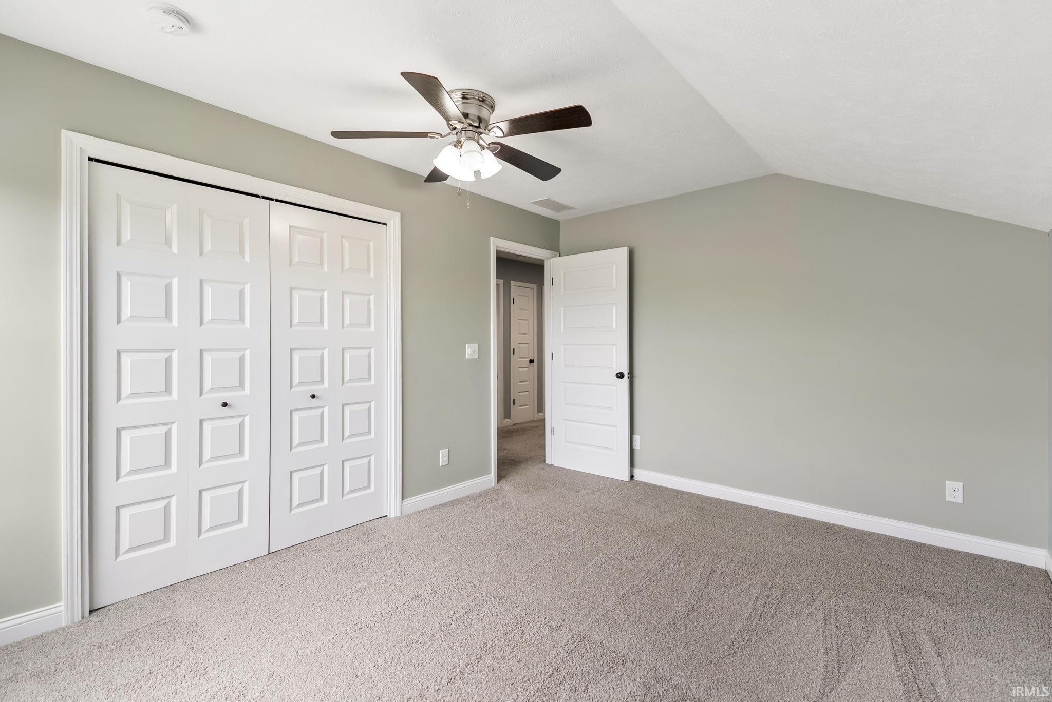 Bedroom featuring soft gray wall paint, light-toned carpet flooring, and a ceiling fan with integrated lighting