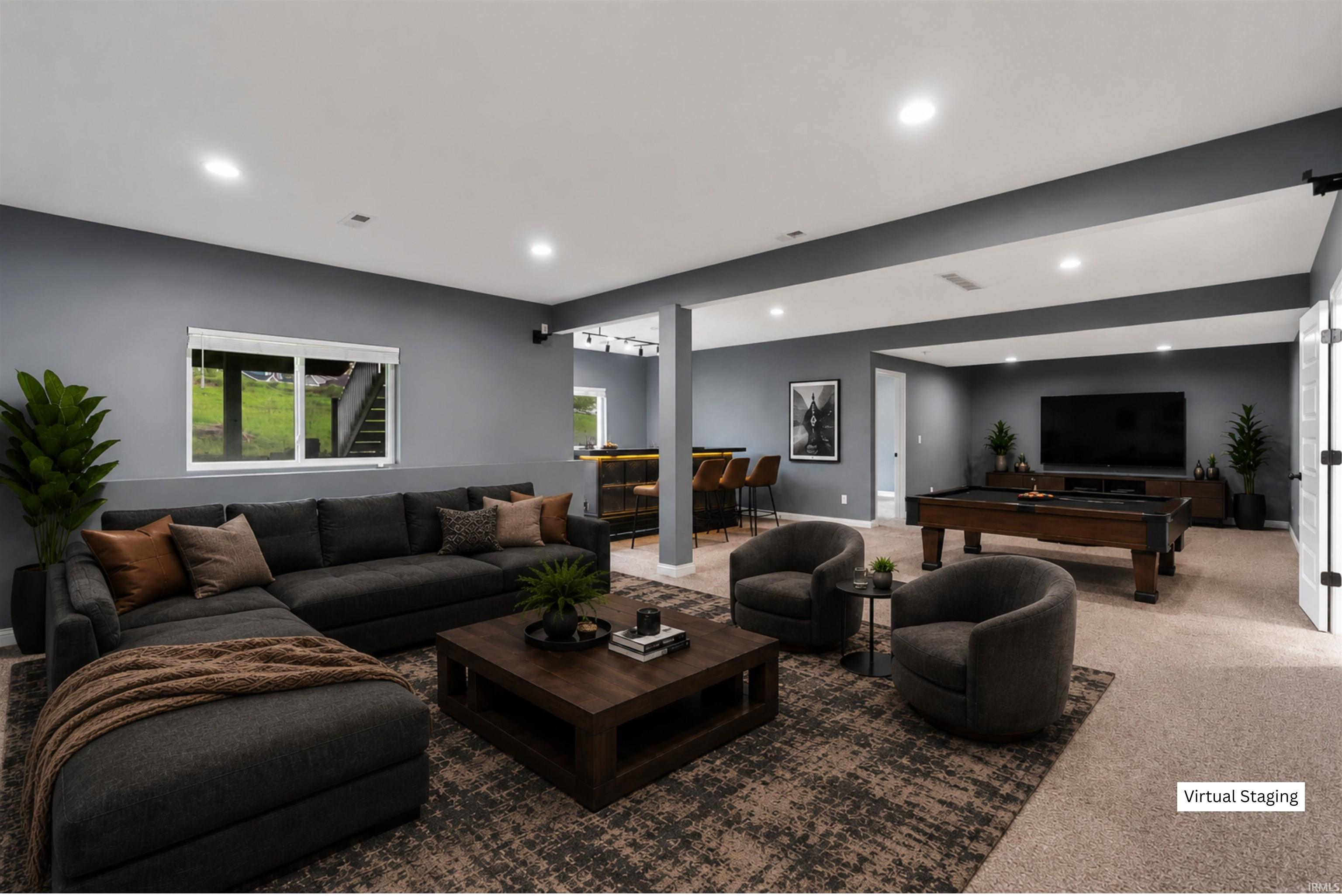 Spacious lower-level entertainment area featuring recessed lighting, a built-in bar with seating, carpeting, and a window with exterior visibility