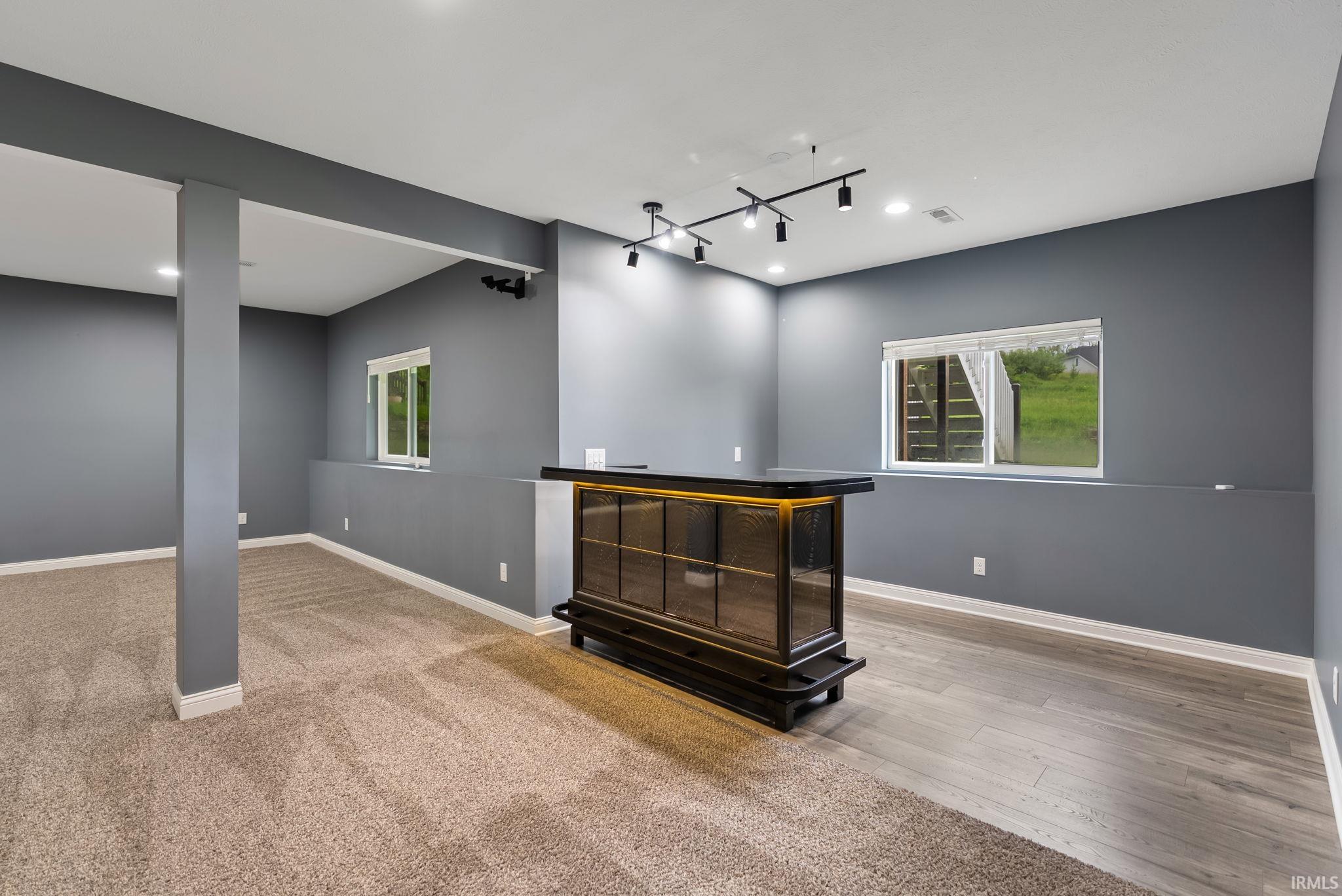 Finished basement with a built-in bar featuring a dark countertop and glass-front cabinetry