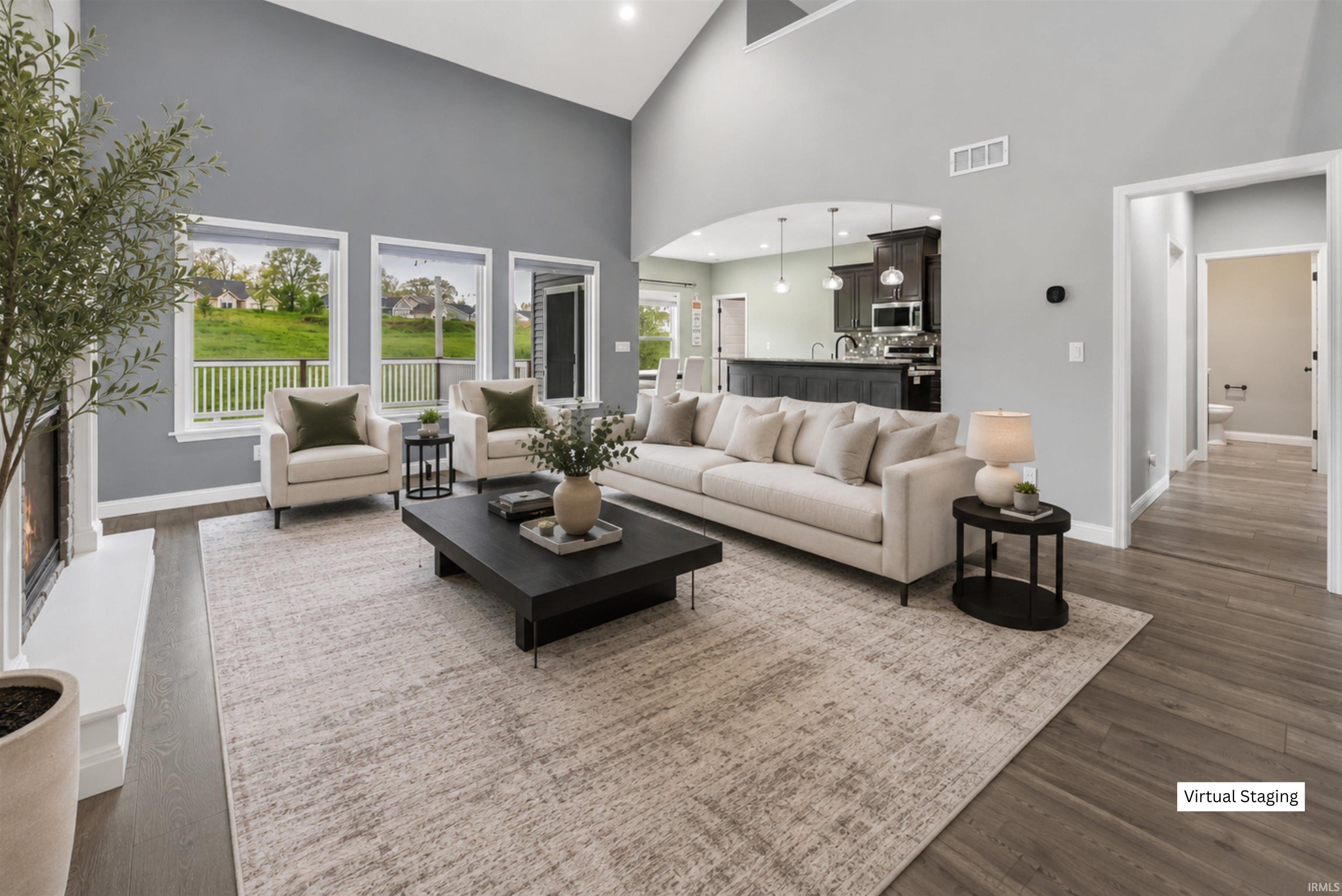 Vaulted living space featuring wood-finish flooring, a white mantel, and ample natural light through multiple windows