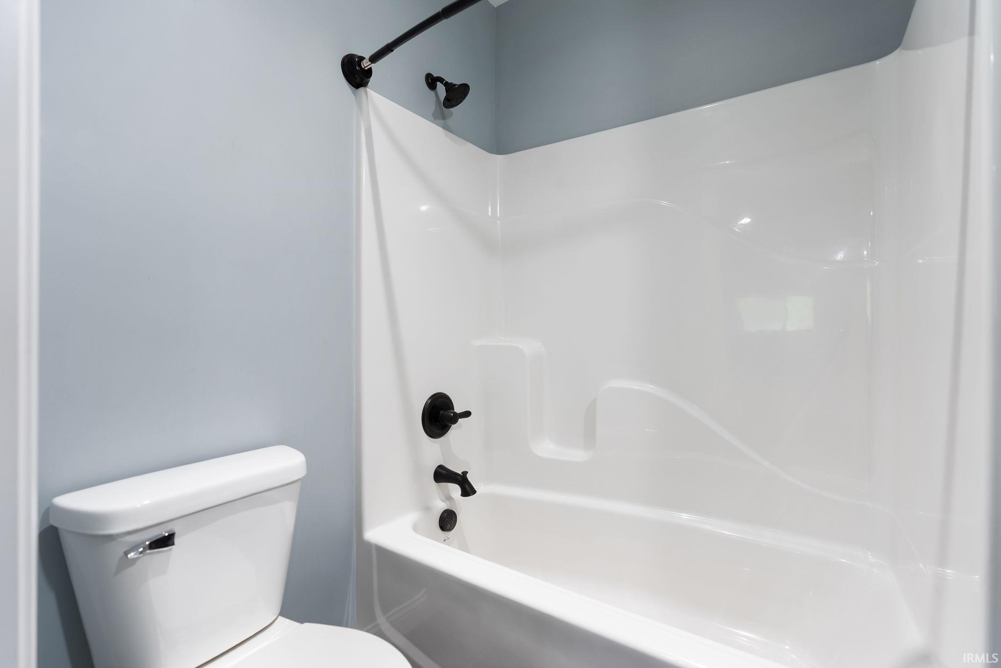 White fiberglass tub and shower combination with matte black fixtures