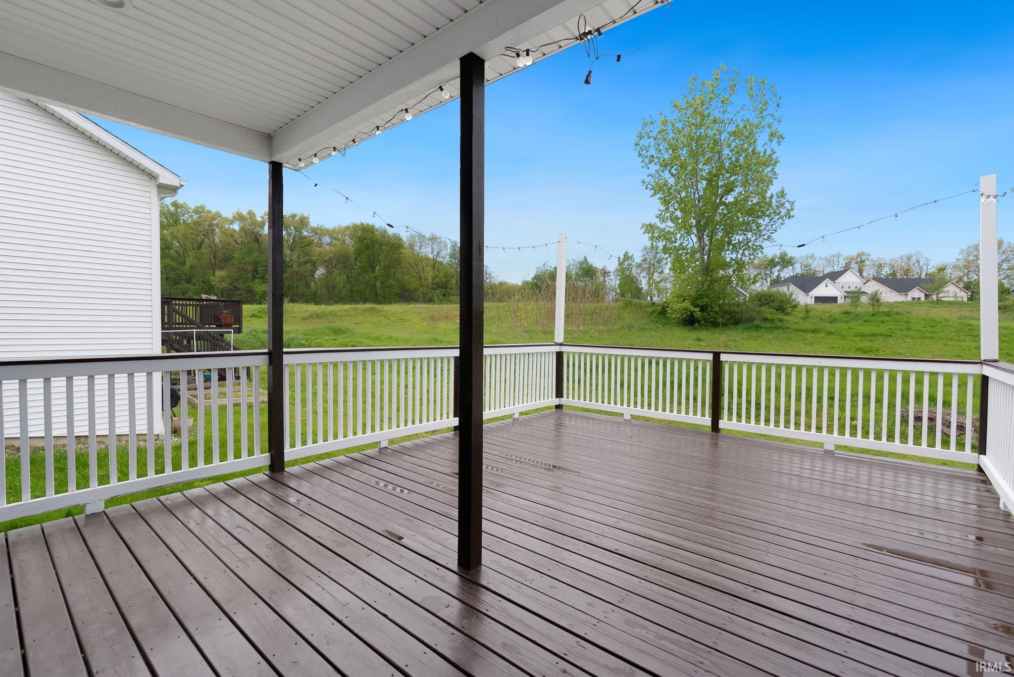 Spacious covered deck featuring dark wood-finish flooring and white railings