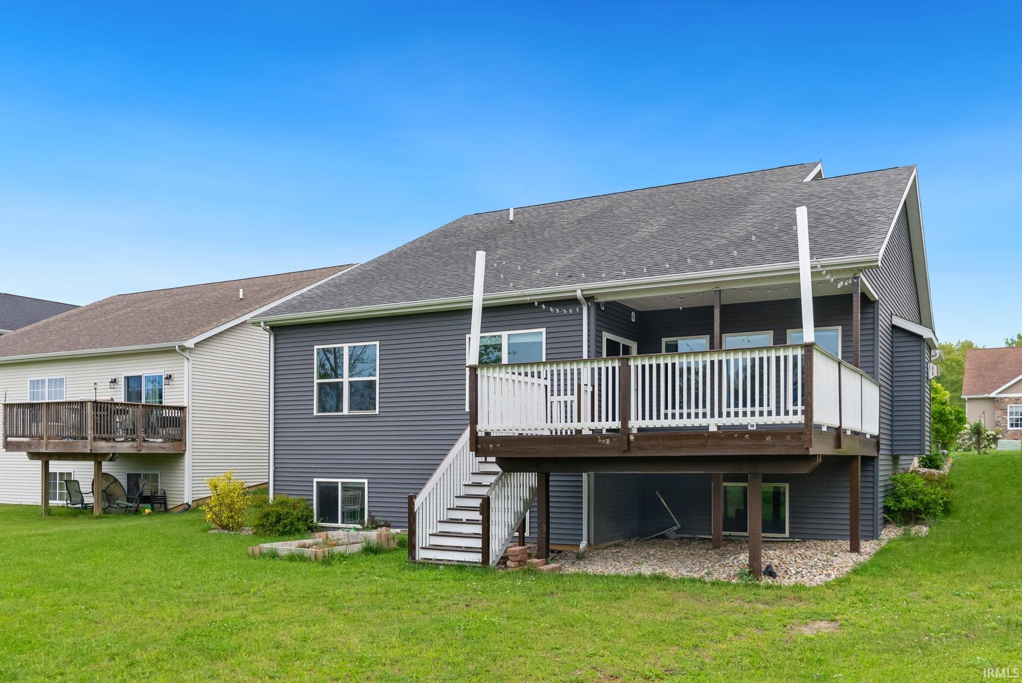 Rear exterior showcasing a multi-level deck with white railings, stairs, and dark grey siding