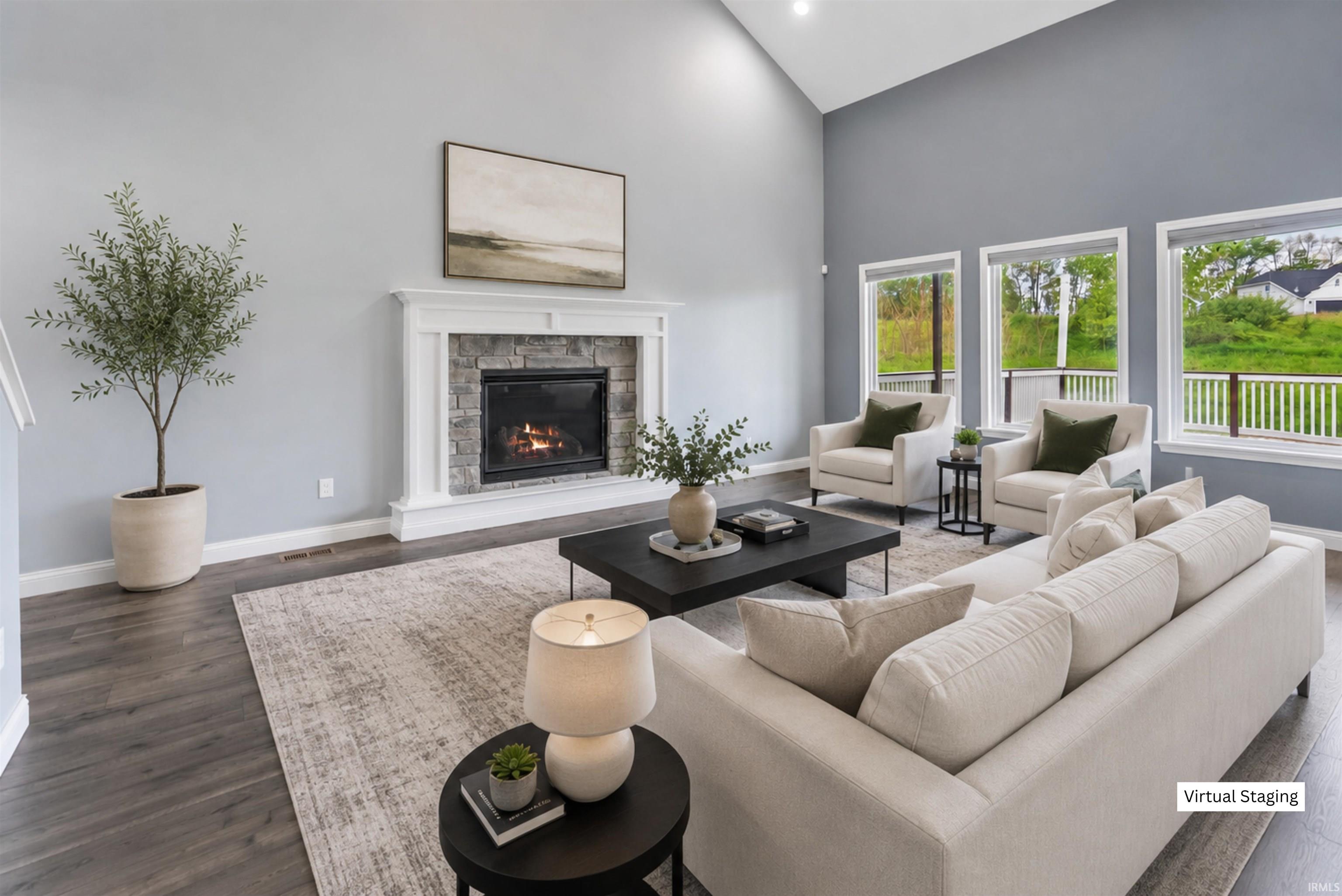 Living area featuring a stone fireplace with a white mantel, wood-finish flooring, and vaulted ceilings