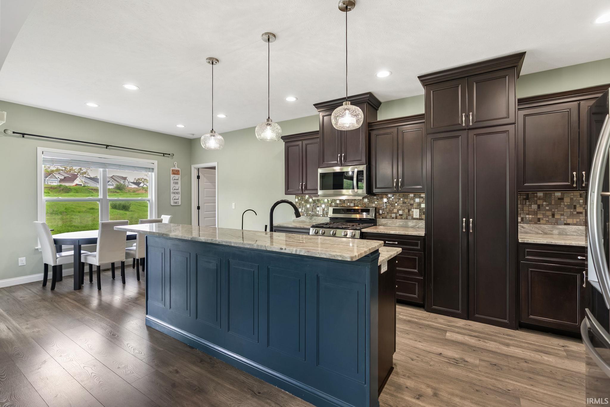 Kitchen featuring a central island with a contrasting blue base, light-toned countertop, and three pendant lights