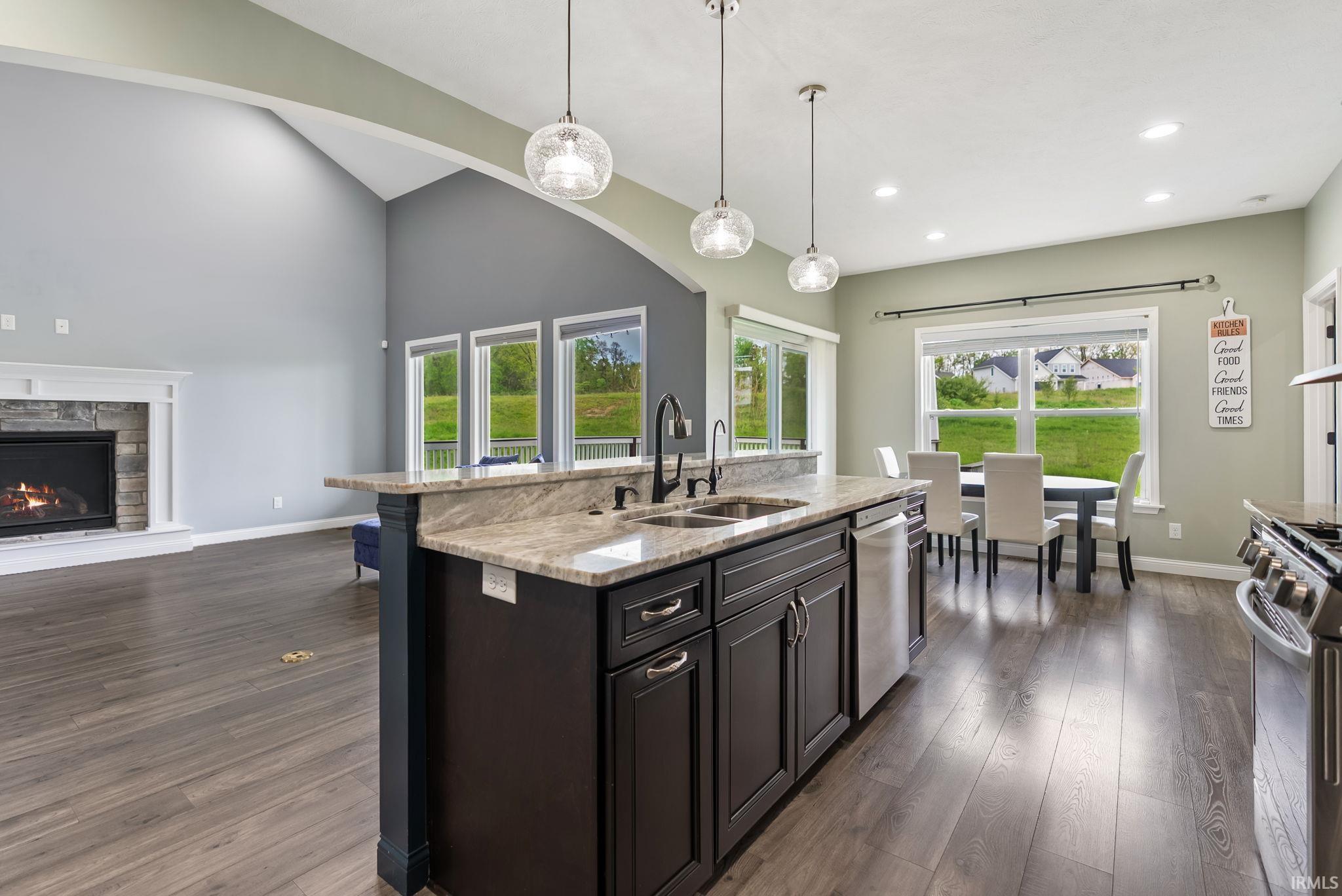 Kitchen island with a double basin sink, dark cabinetry, and light-toned countertop