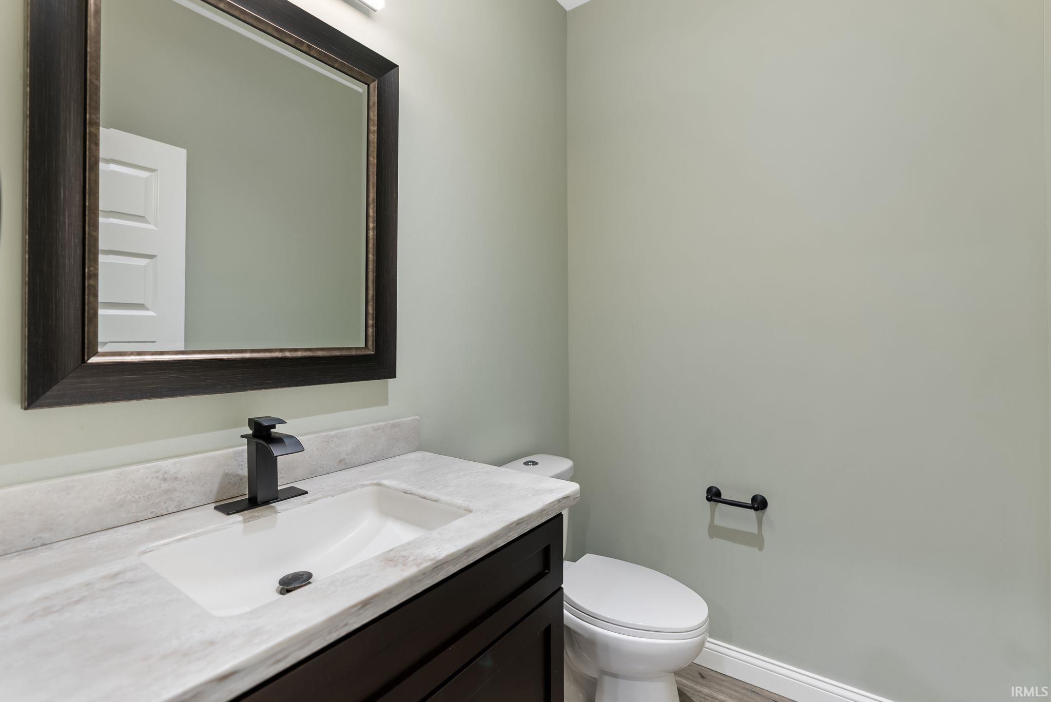 Bathroom vanity featuring an integrated rectangular sink, gray-veined countertop, and dark wood-finish cabinetry