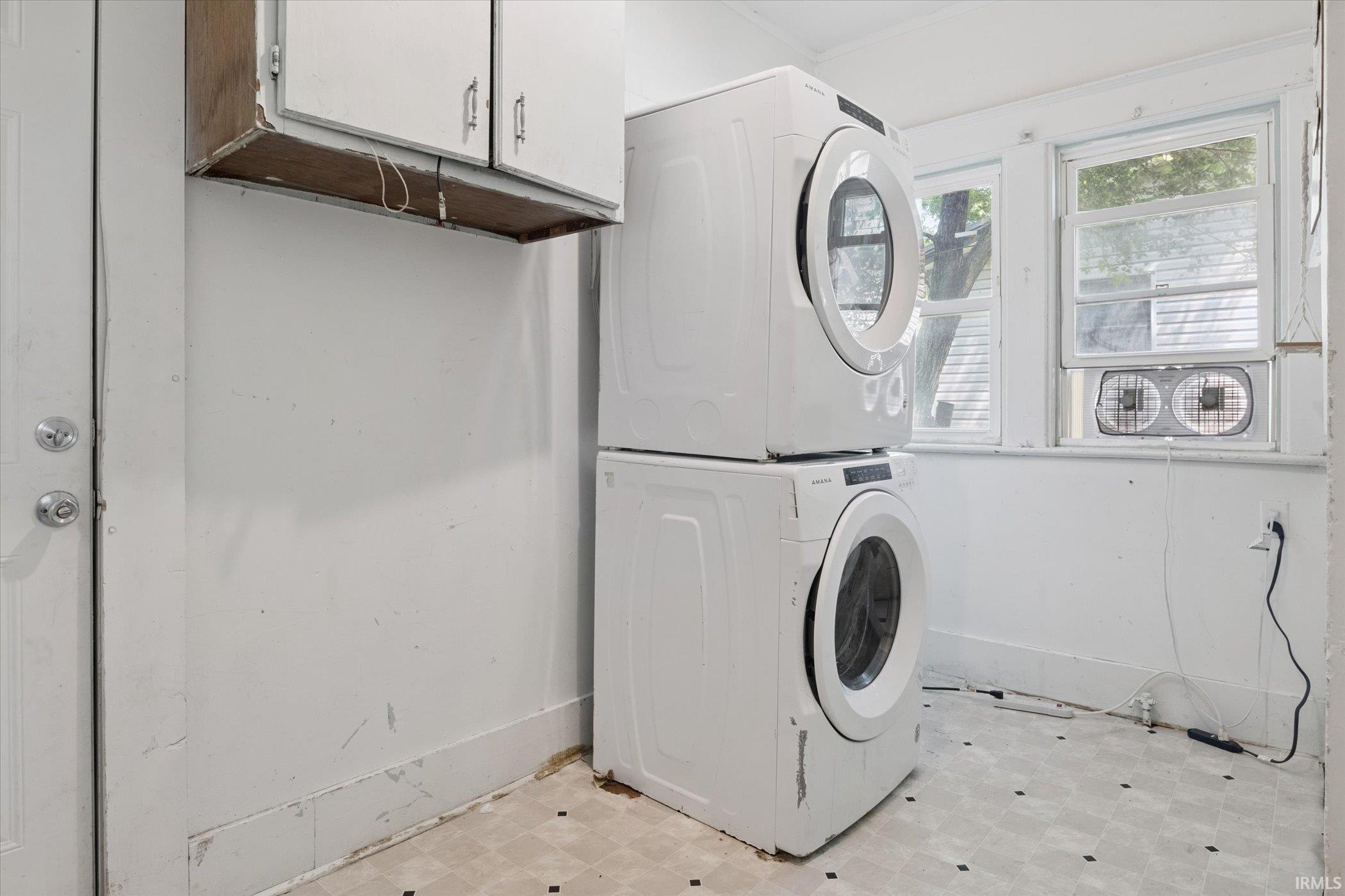 Compact laundry area featuring wall-mounted cabinetry, white walls, and pattern flooring