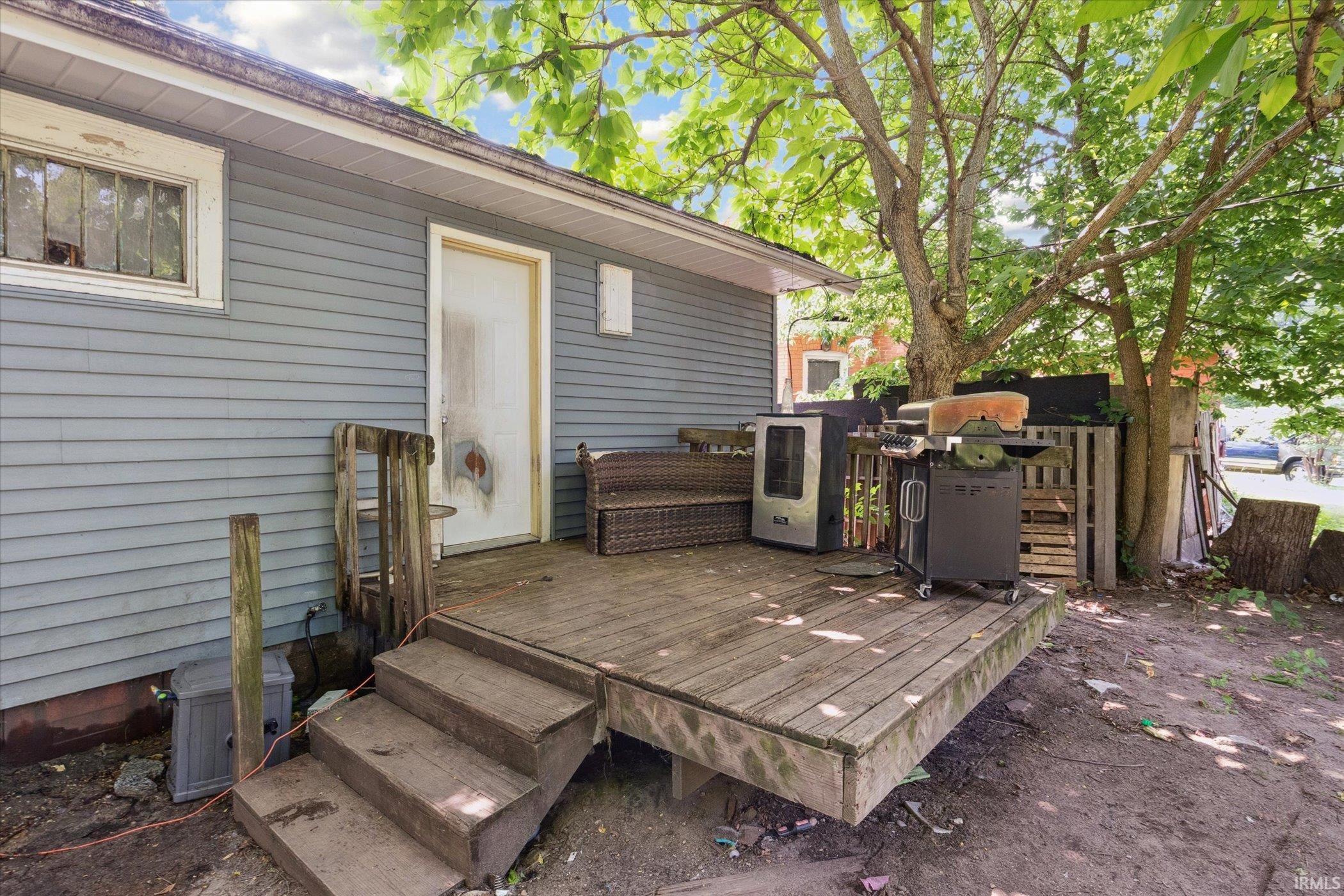 Exterior wood deck with direct access to the structure, featuring gray siding and a white entry door